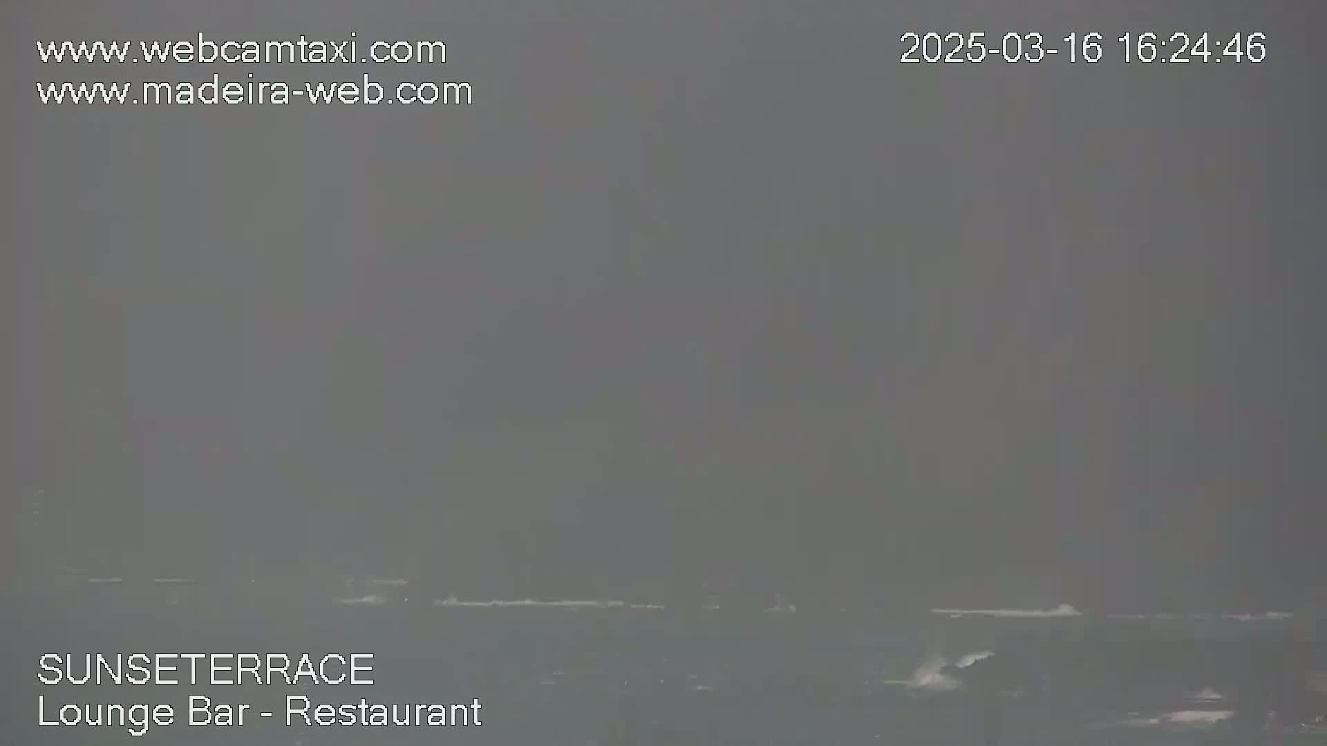A hazy, overcast view shows a dark gray ocean with small waves.
