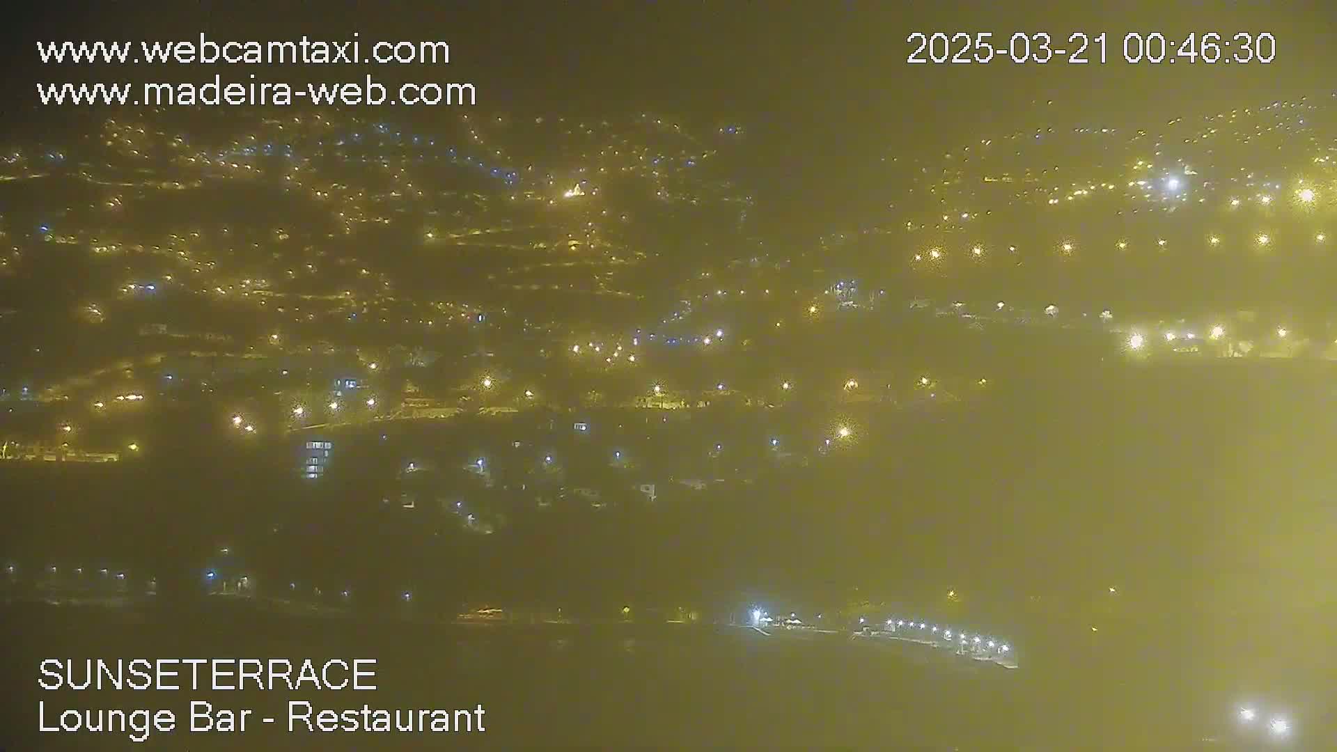 A hazy, nighttime view of a town speckled with numerous lights.