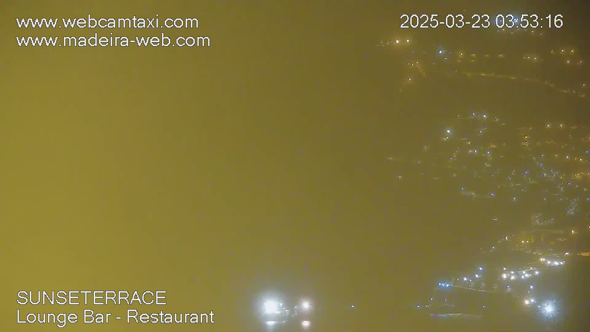A hazy, nighttime view of numerous lights from a distant town or city.