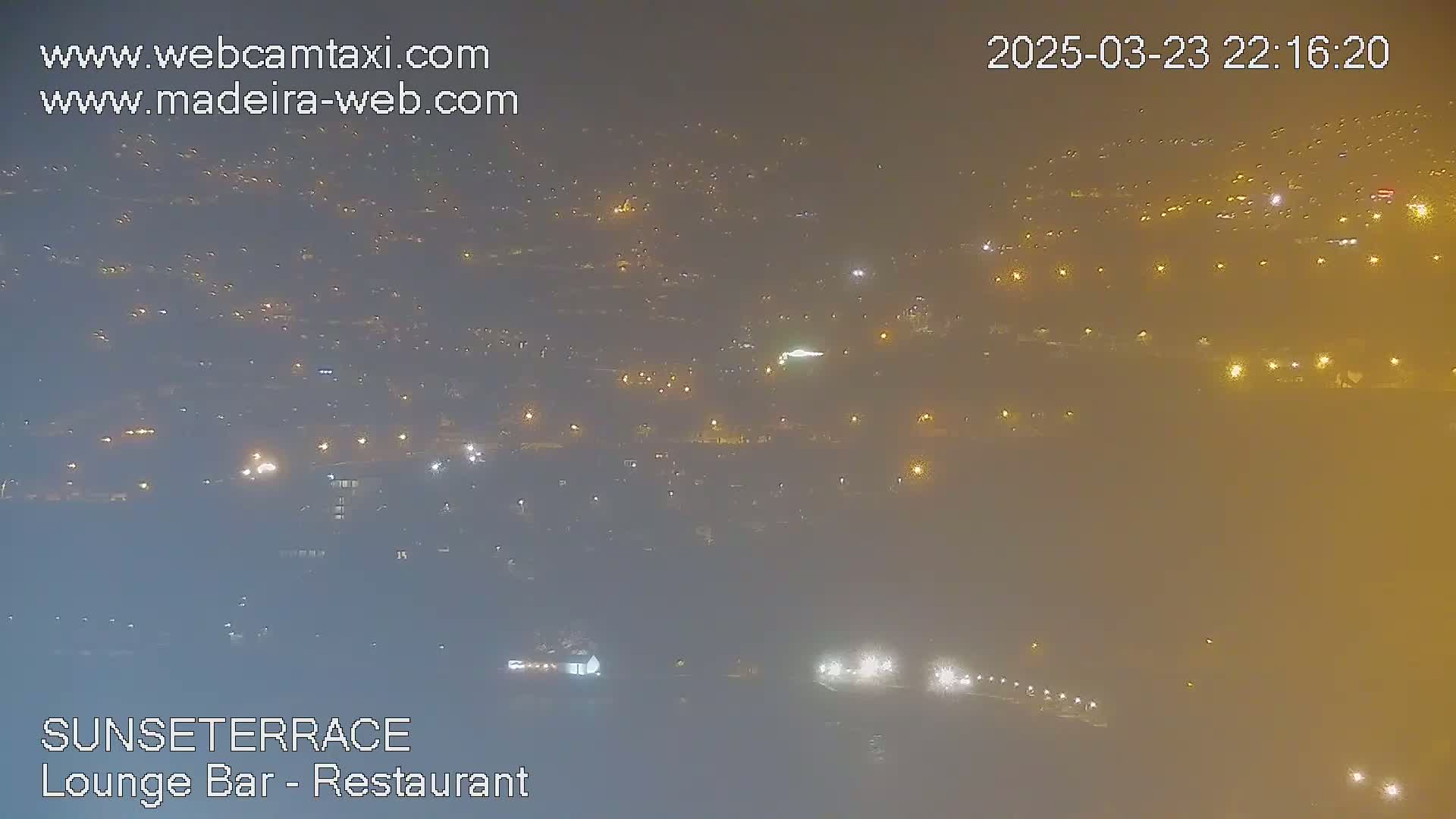 A hazy, nighttime aerial view of a city with numerous illuminated buildings and roads.