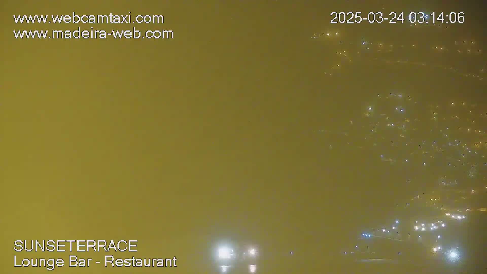 A hazy, nighttime view shows numerous lights in the distance, possibly a city or town.