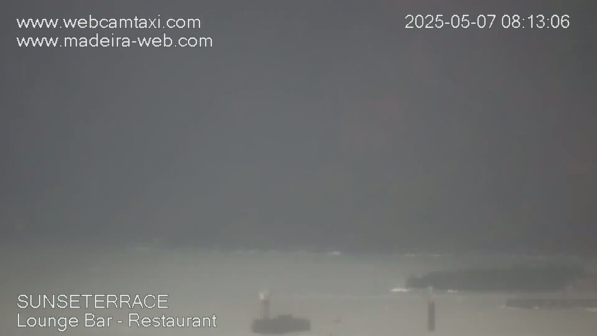 A hazy, overcast day reveals a distant coastline with dark, choppy water.