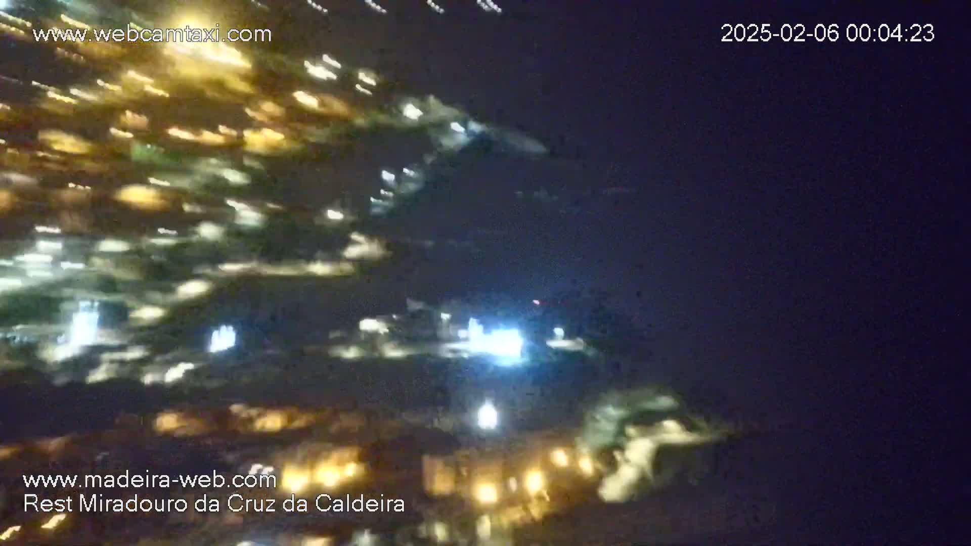 A blurry nighttime image shows numerous lights, likely from a town or city, under a clear, dark sky.