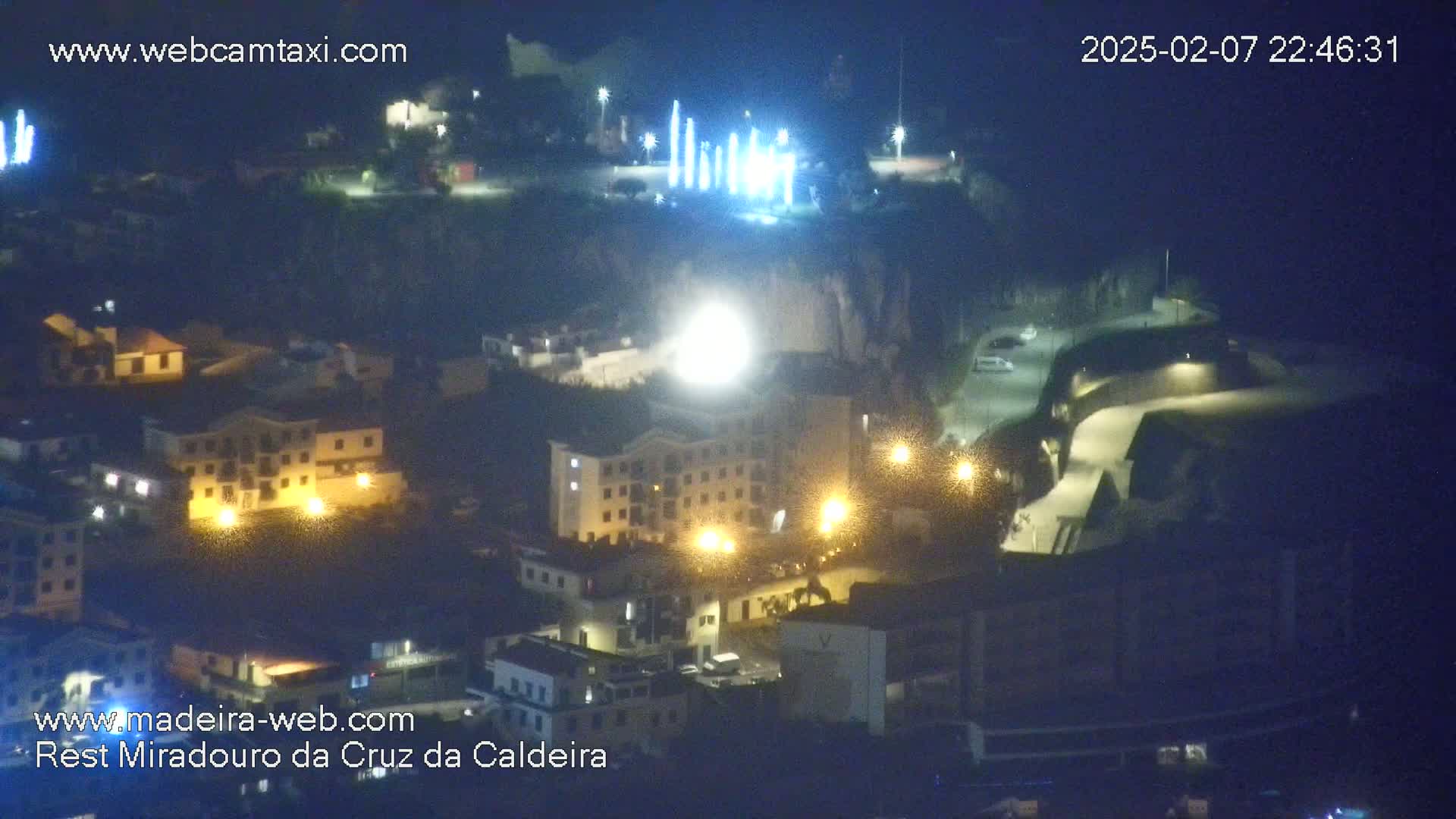 A nighttime aerial view of a town with illuminated buildings and streets, under a dark sky.