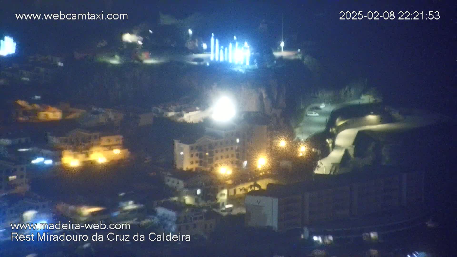 A nighttime aerial view shows a town illuminated by streetlights and building lights, under a clear, dark sky.