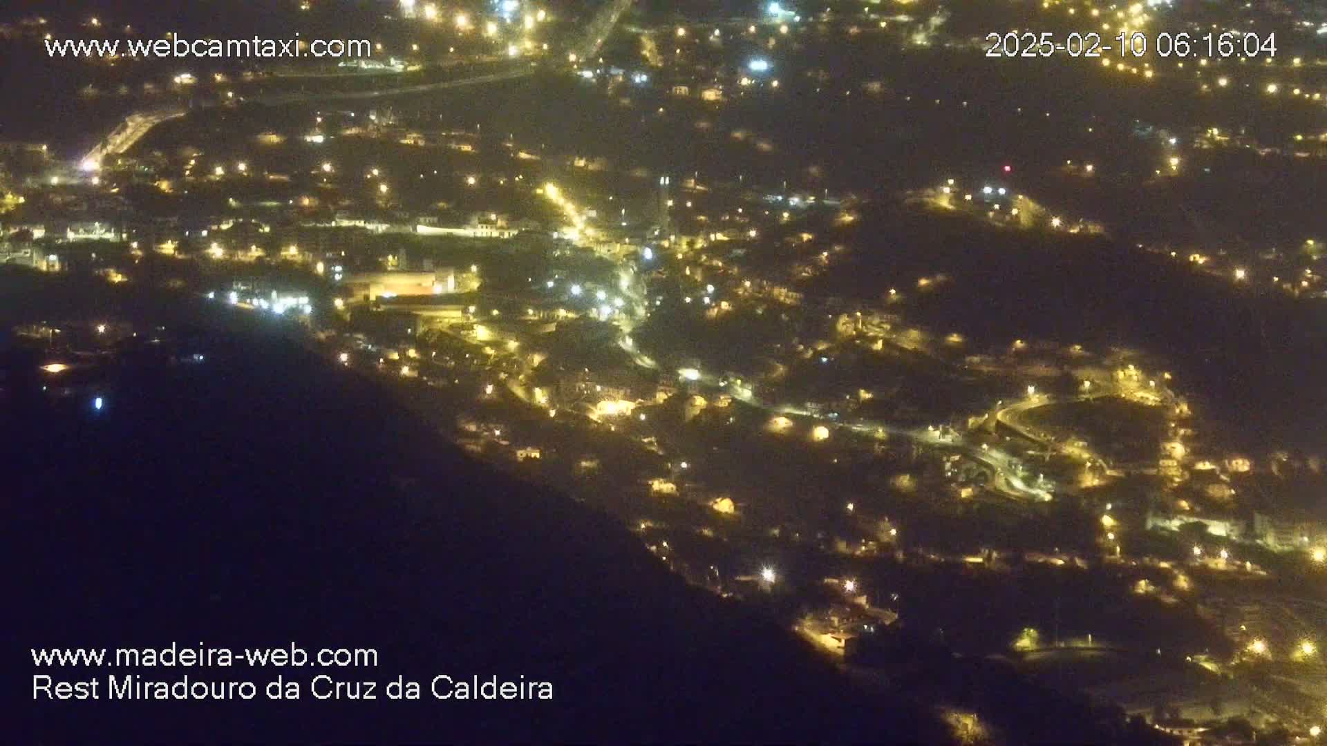 A nighttime, high-angle view of a town illuminated by many small lights nestled into a hillside.
