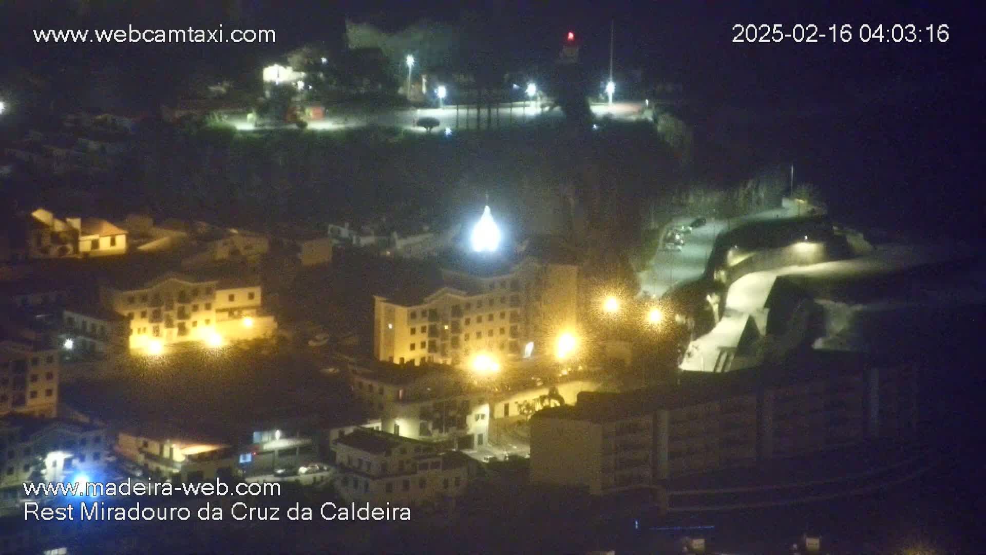 An elevated nighttime view of a town with illuminated buildings and streets.