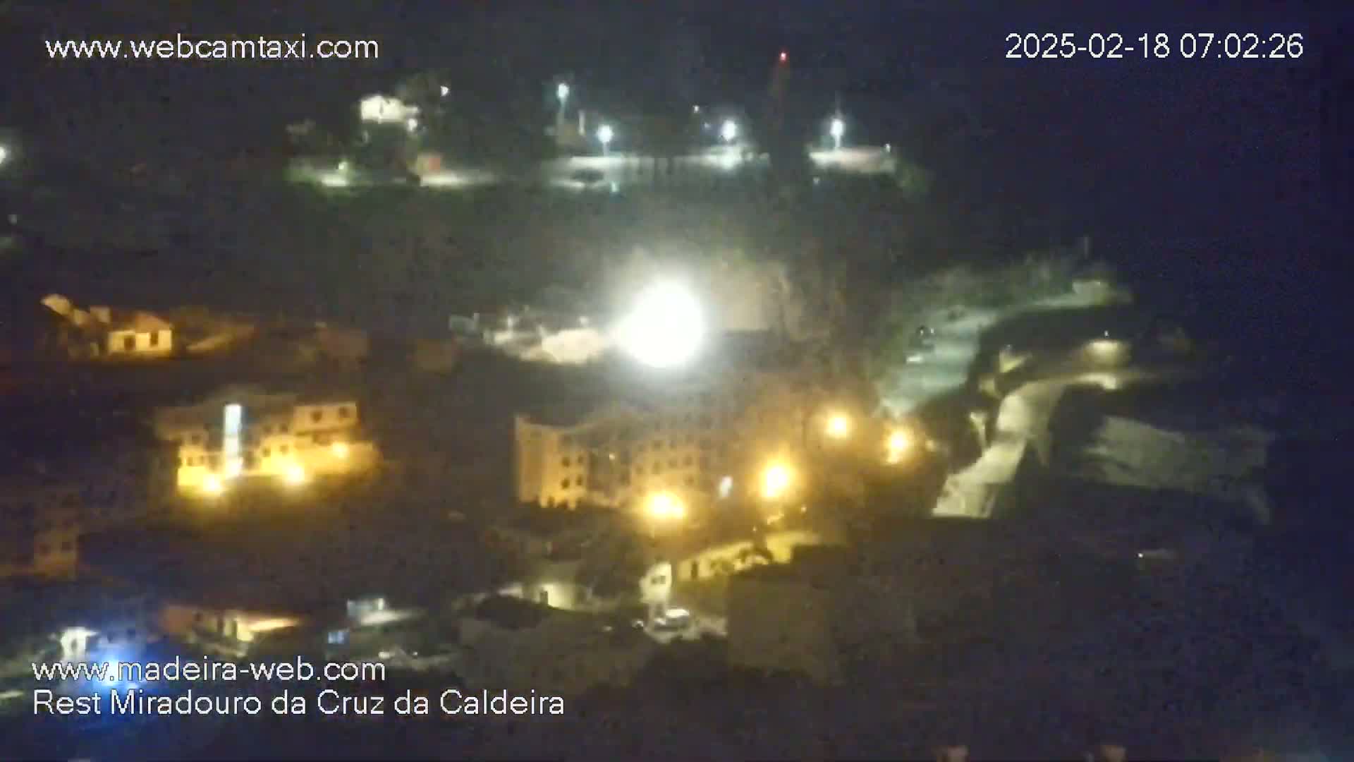 A nighttime, long shot of a town with illuminated buildings, possibly under a clear sky.