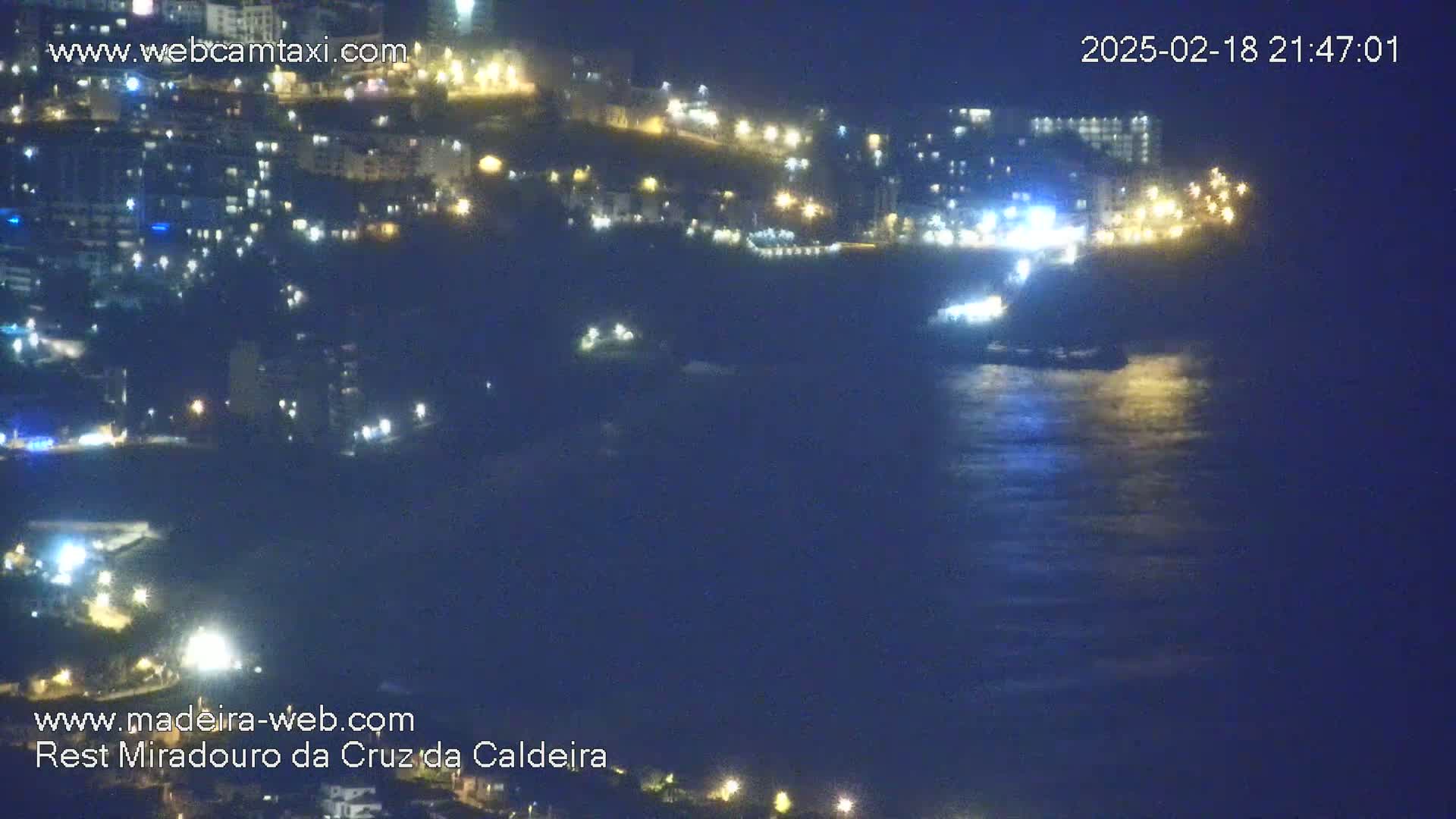 A nighttime view of a city's lights along a dark, somewhat choppy ocean.