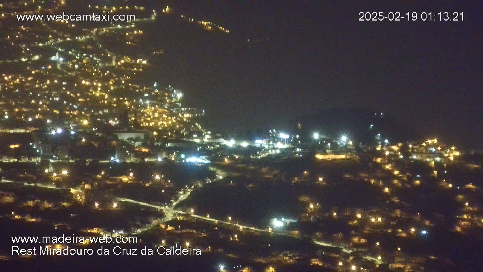 A nighttime, high-angle view shows a sprawling town illuminated by countless small lights.