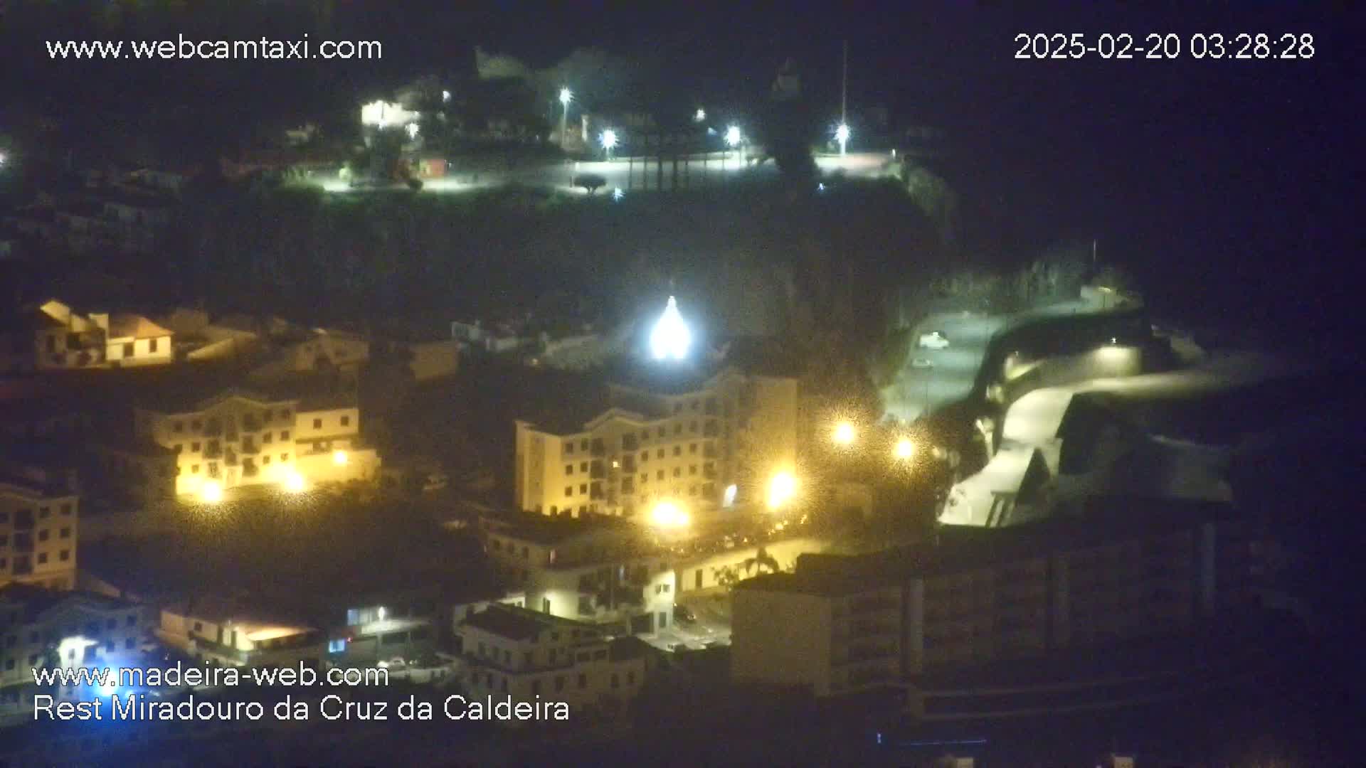 A nighttime, high-angle view of a town illuminated by streetlights and building lights.