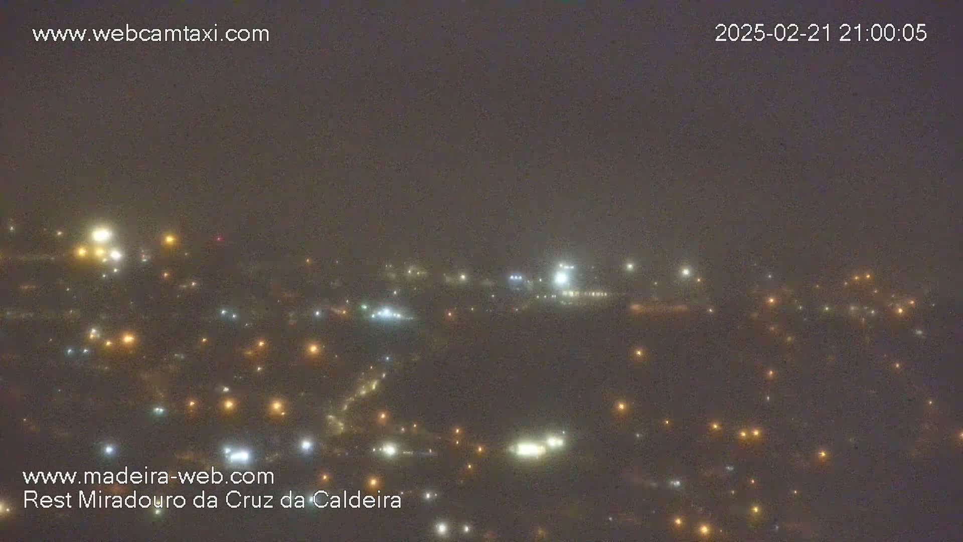 A hazy night scene shows a distant town speckled with numerous small lights.