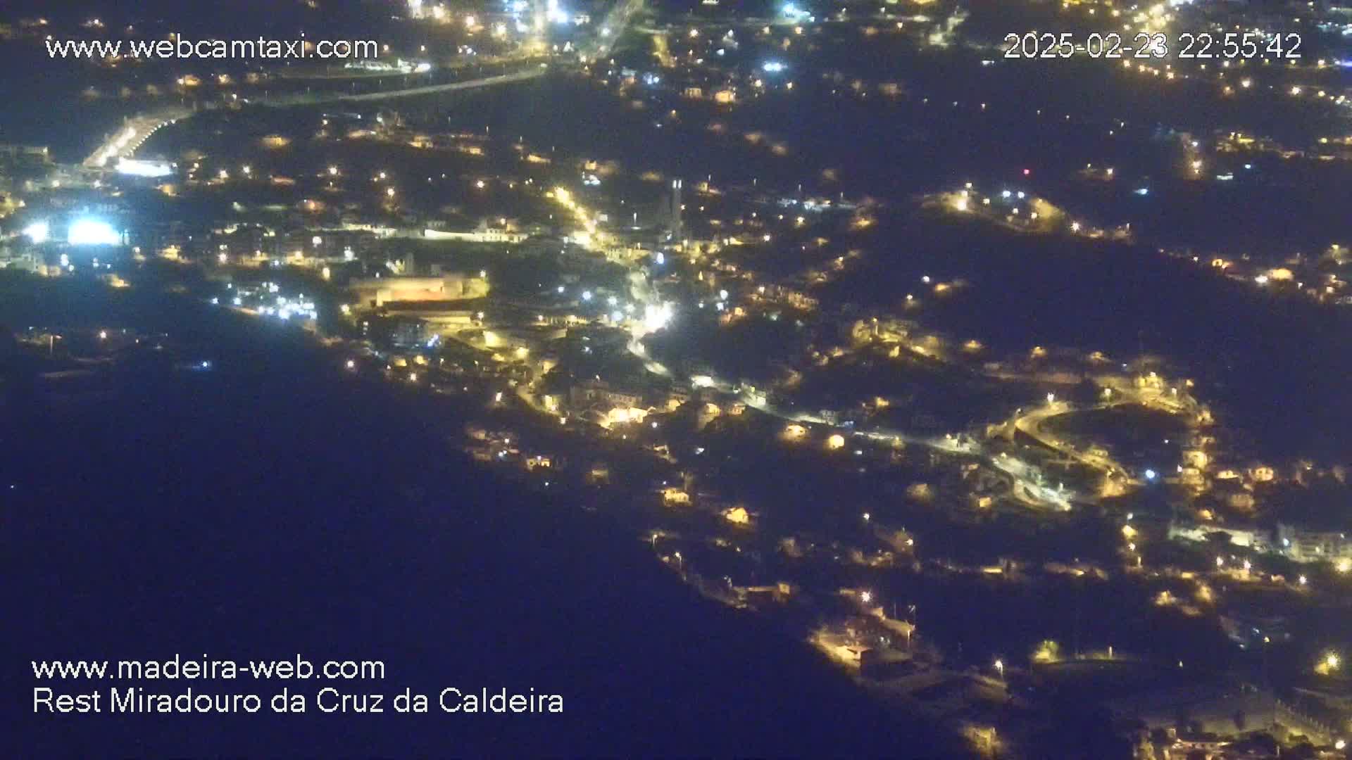 A hillside town at night is illuminated by many small lights.