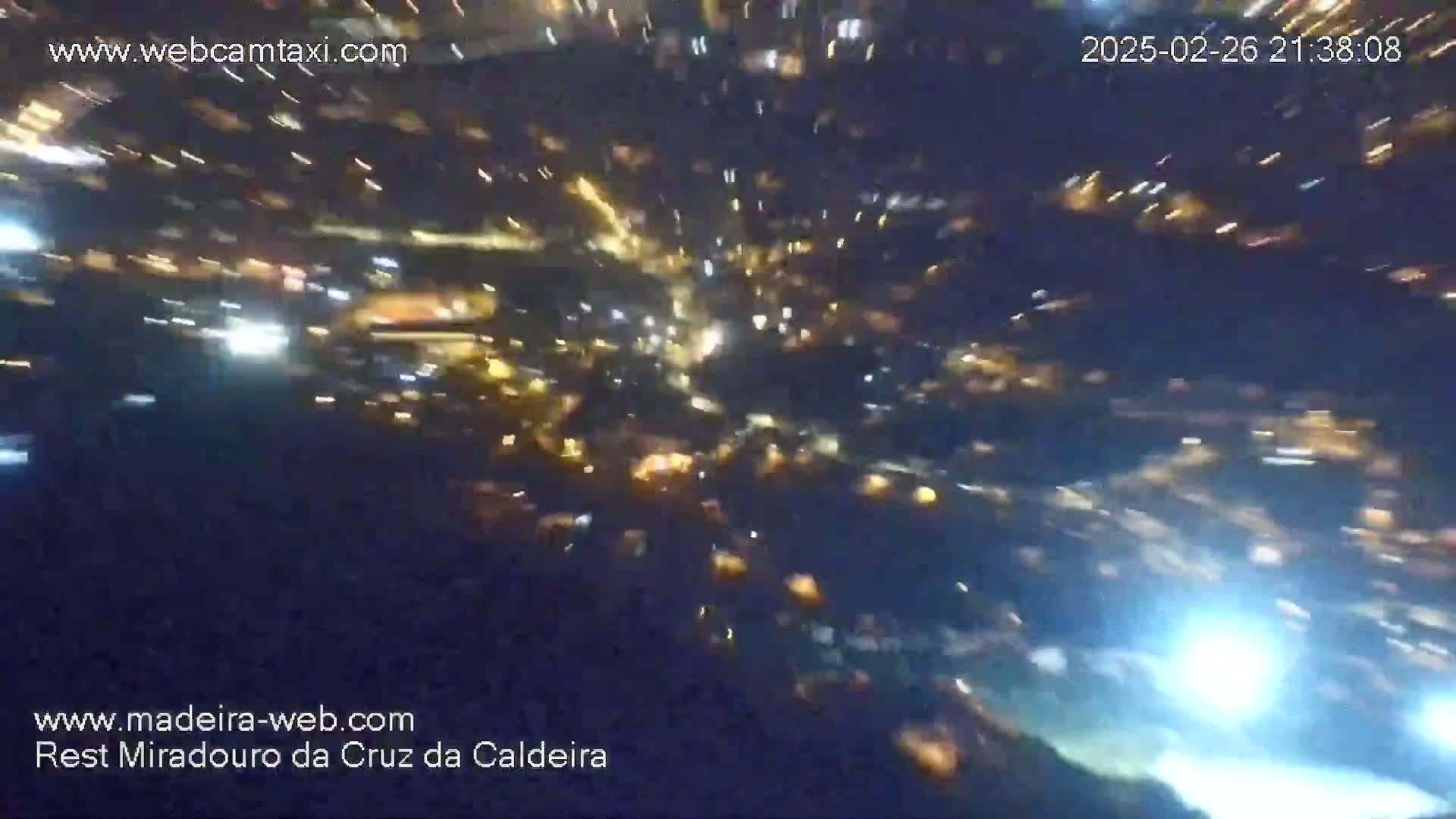 A nighttime, blurry view shows a multitude of bright lights streaking across a dark sky.
