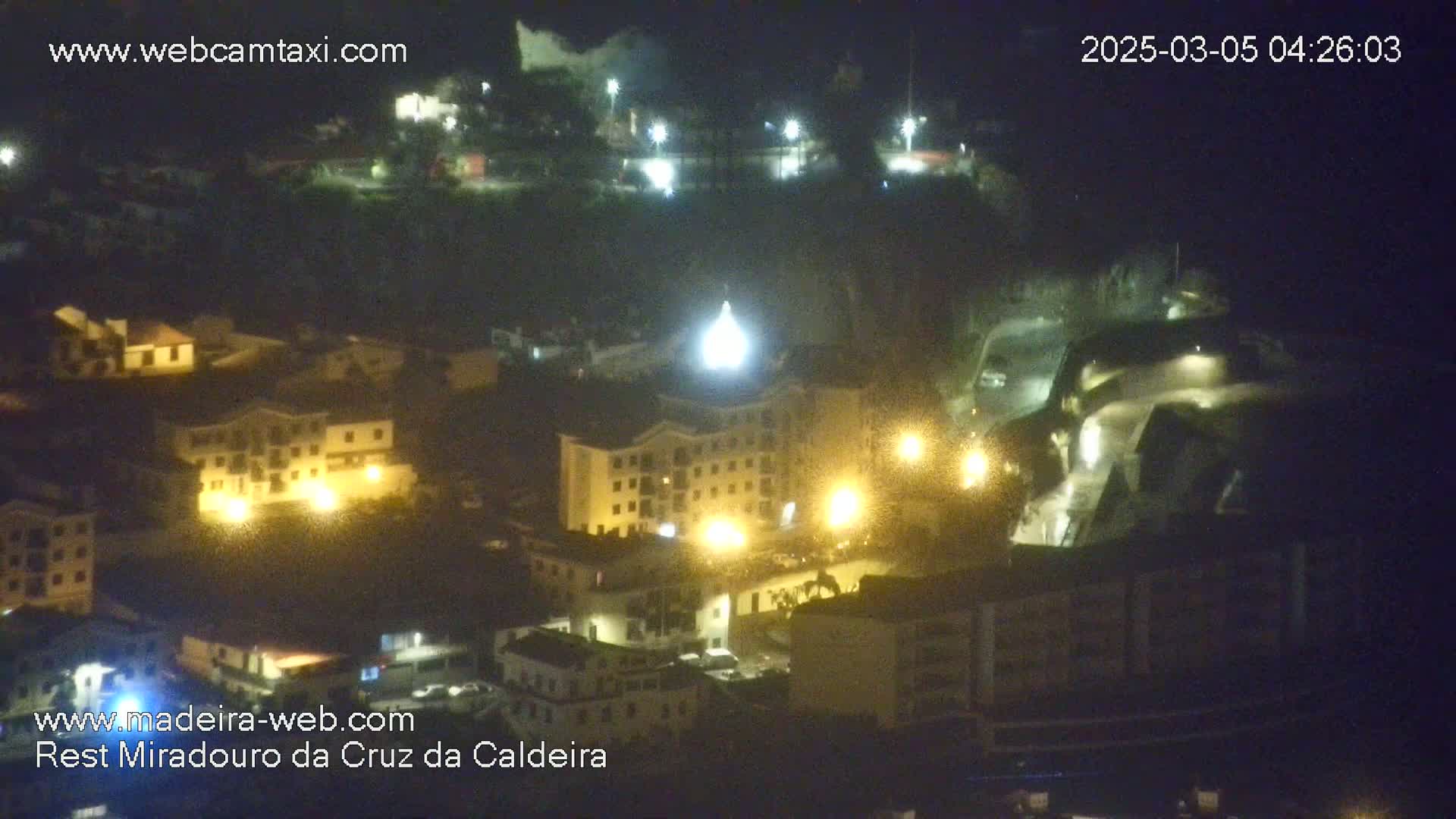 A nighttime, high-angle view shows a town illuminated by streetlights and building lights.