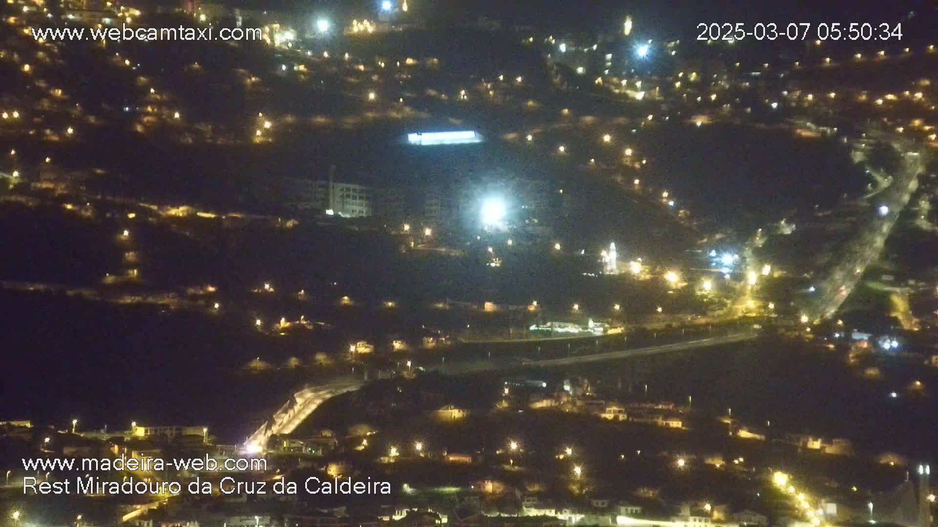A nighttime aerial view of a town illuminated by numerous streetlights, with a clear sky.
