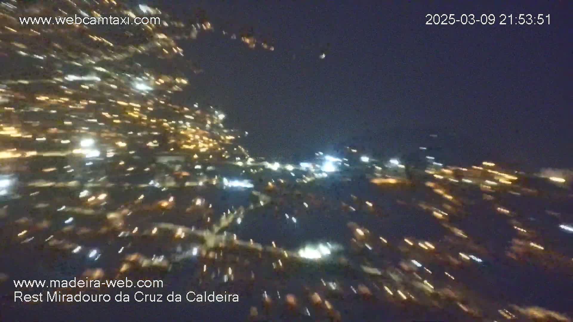 Streaks of light from a city at night are seen from a high vantage point.