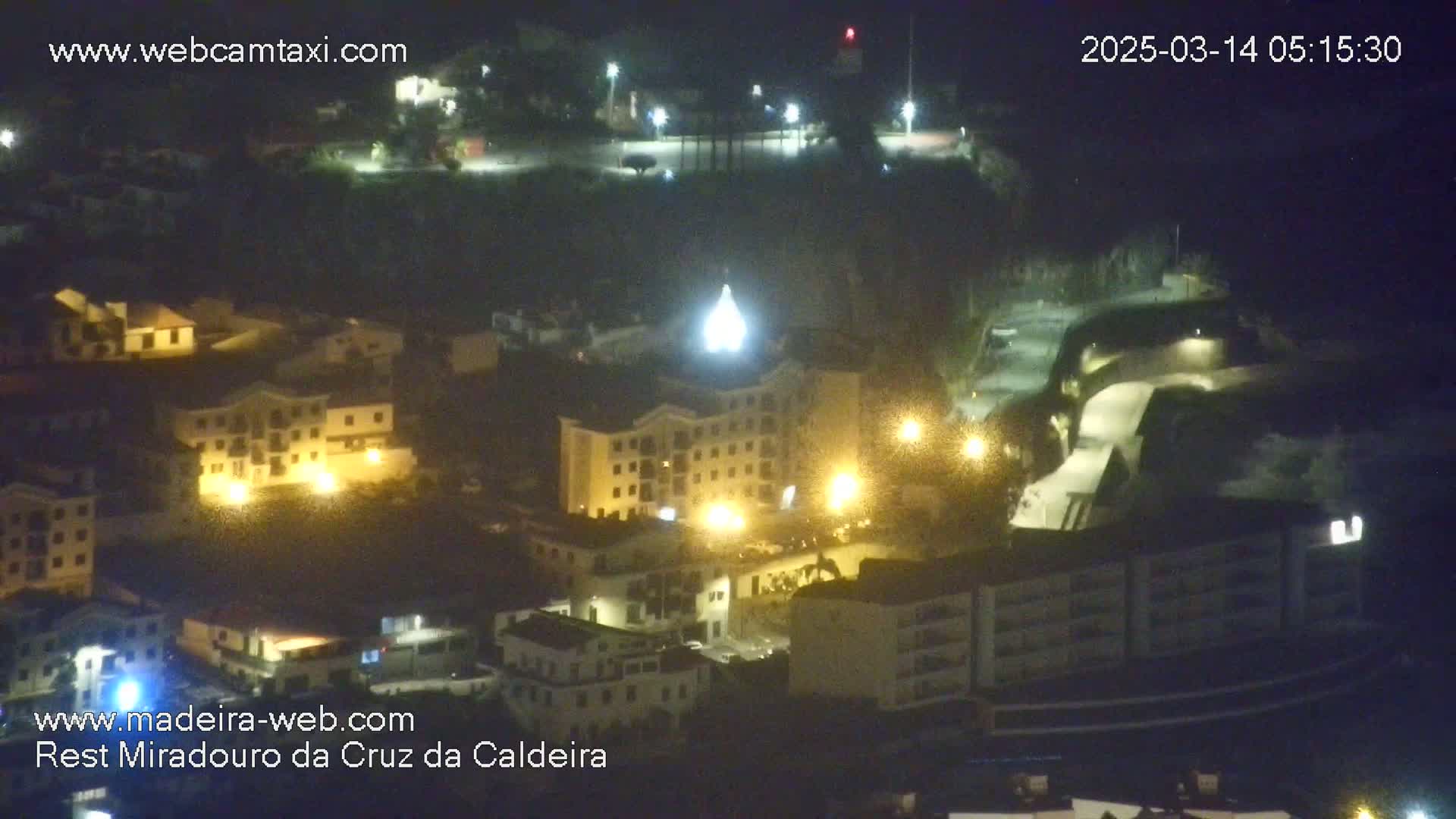 A nighttime, high-angle view of a town with illuminated buildings.