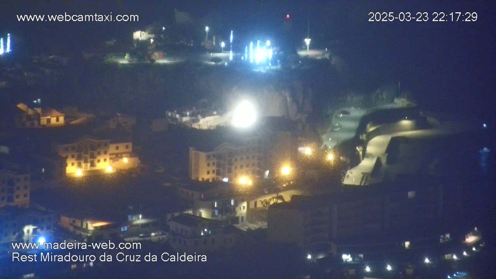 A nighttime, high-angle view of a town illuminated by streetlights and building lights.