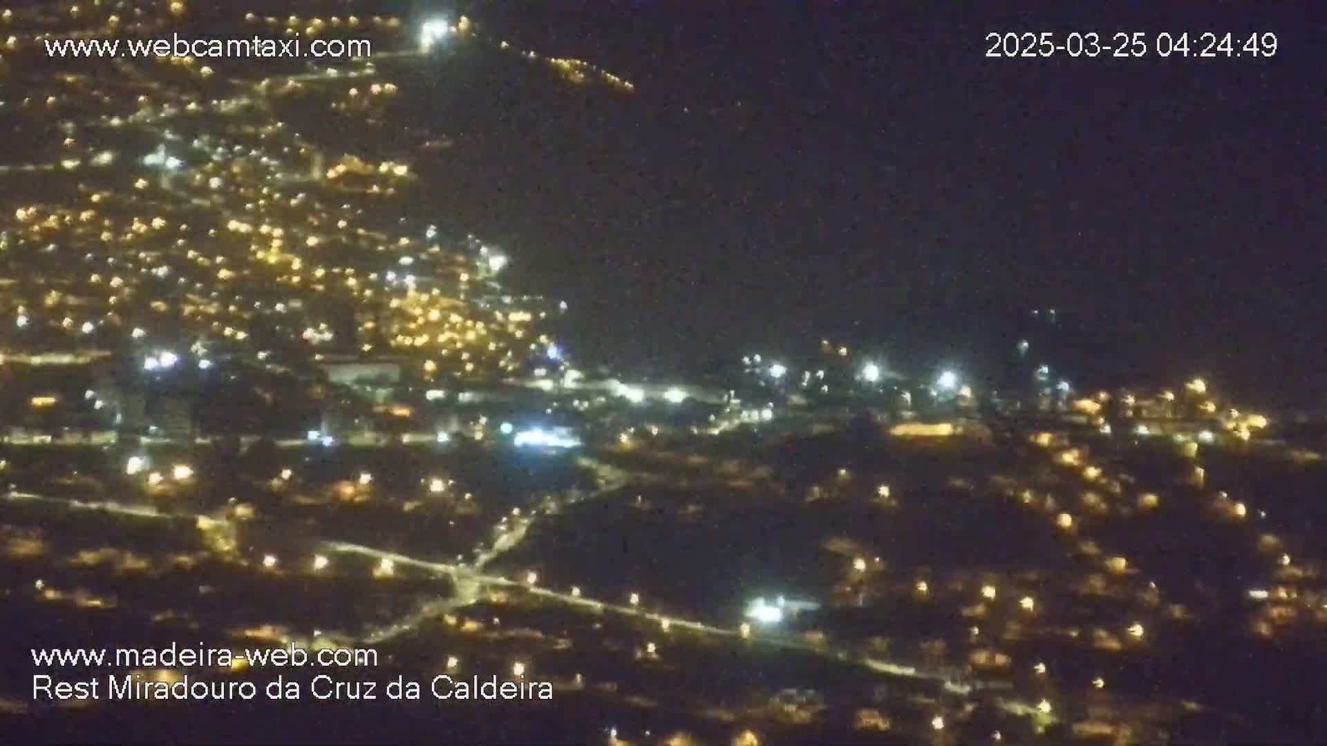 A nighttime, aerial view of a city illuminated by numerous lights spread across a hillside.