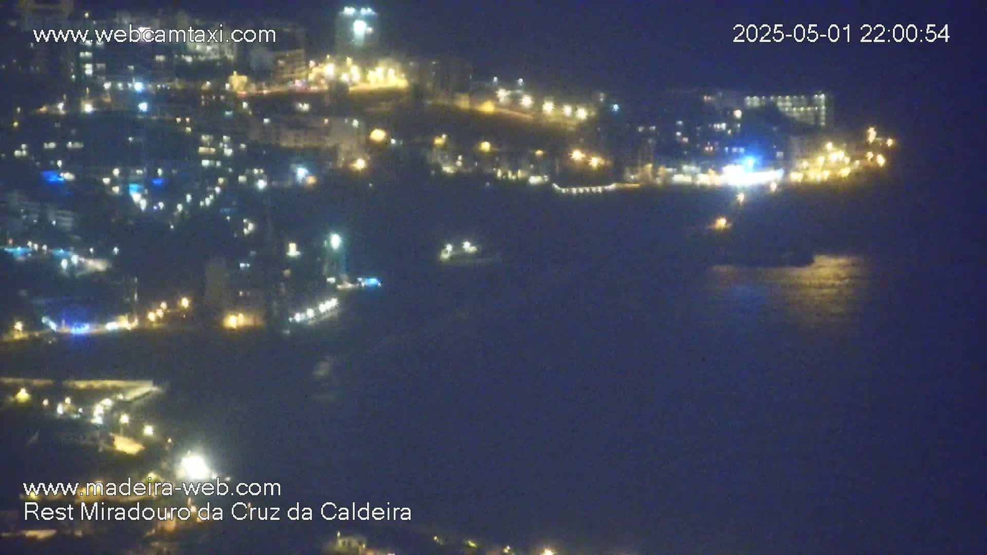A nighttime coastal town with many lights is visible from a distance across dark water.