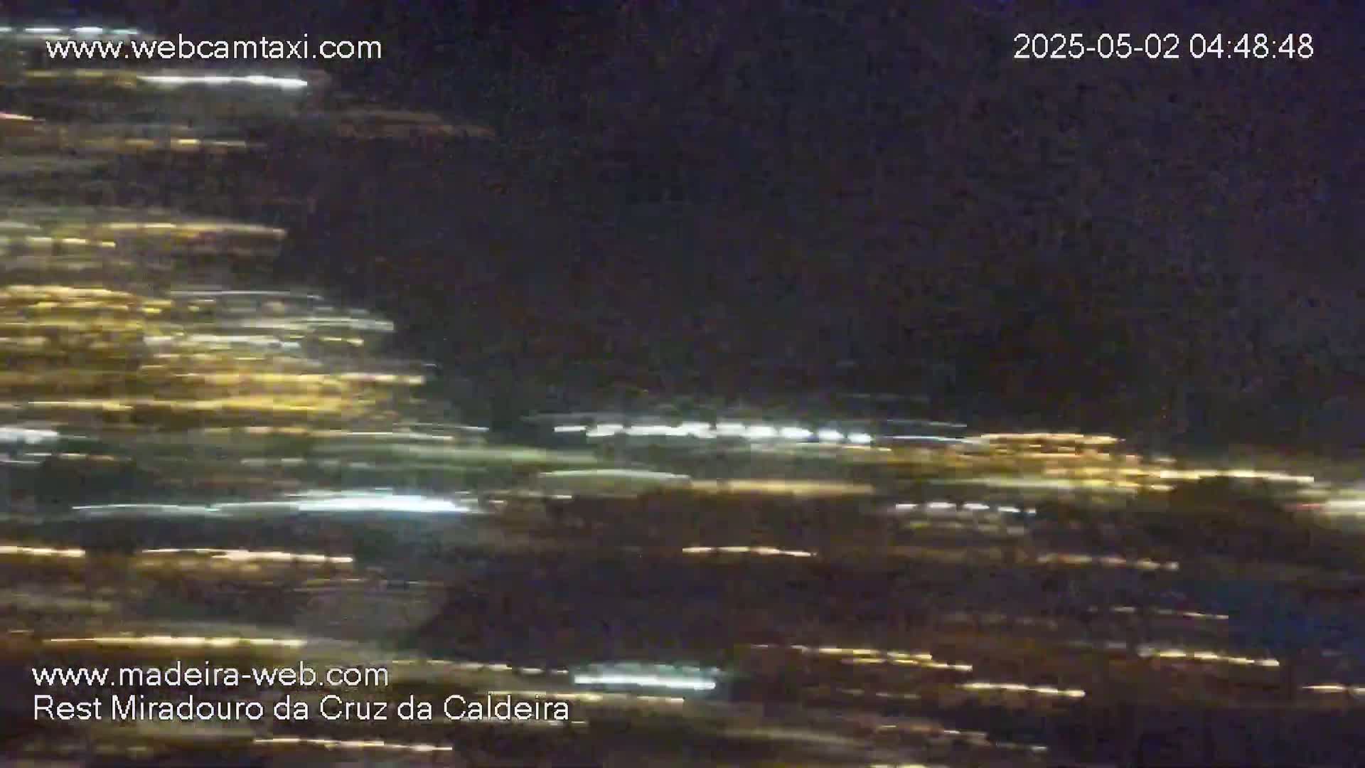 Streaks of light from moving vehicles blur across a dark, nighttime scene.