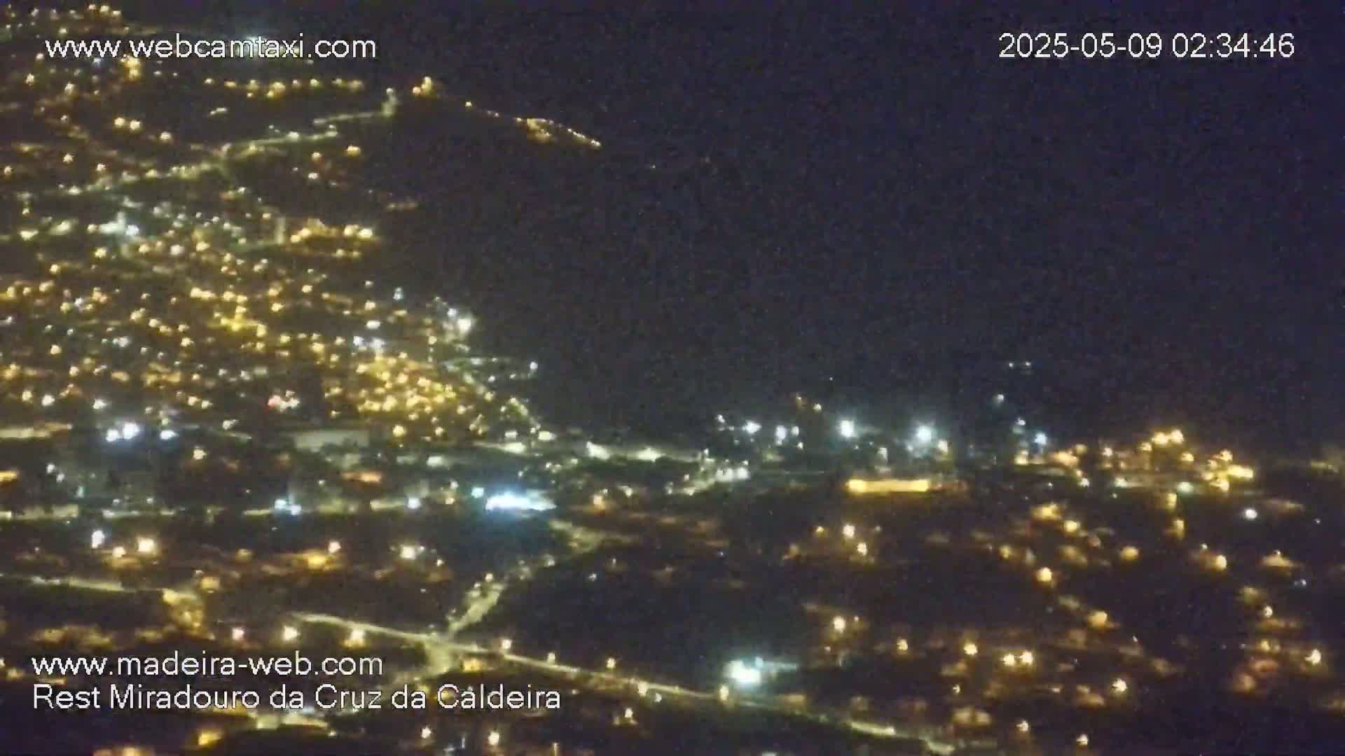 A nighttime, high-angle view shows a sprawling town illuminated by many scattered lights.