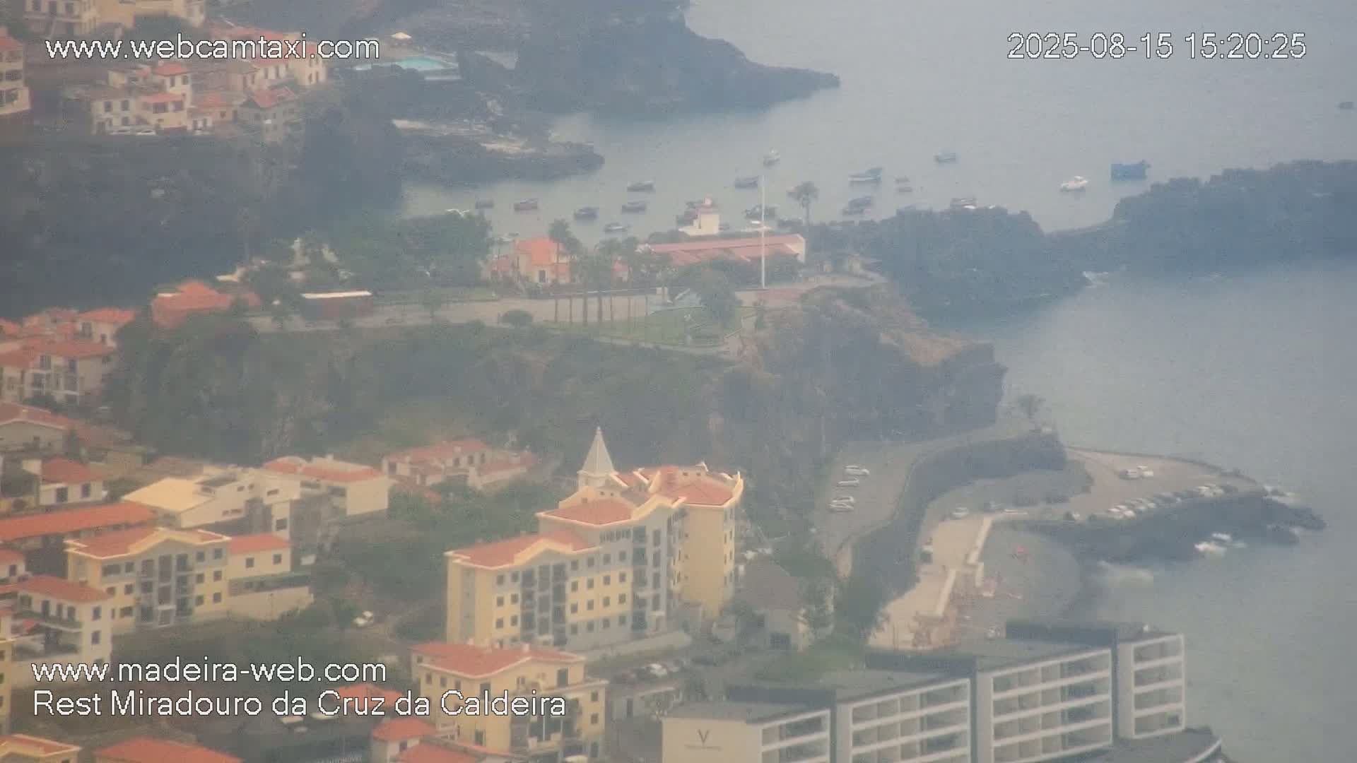 A hazy, long-distance view shows a bridge and a sprawling town nestled among hills.