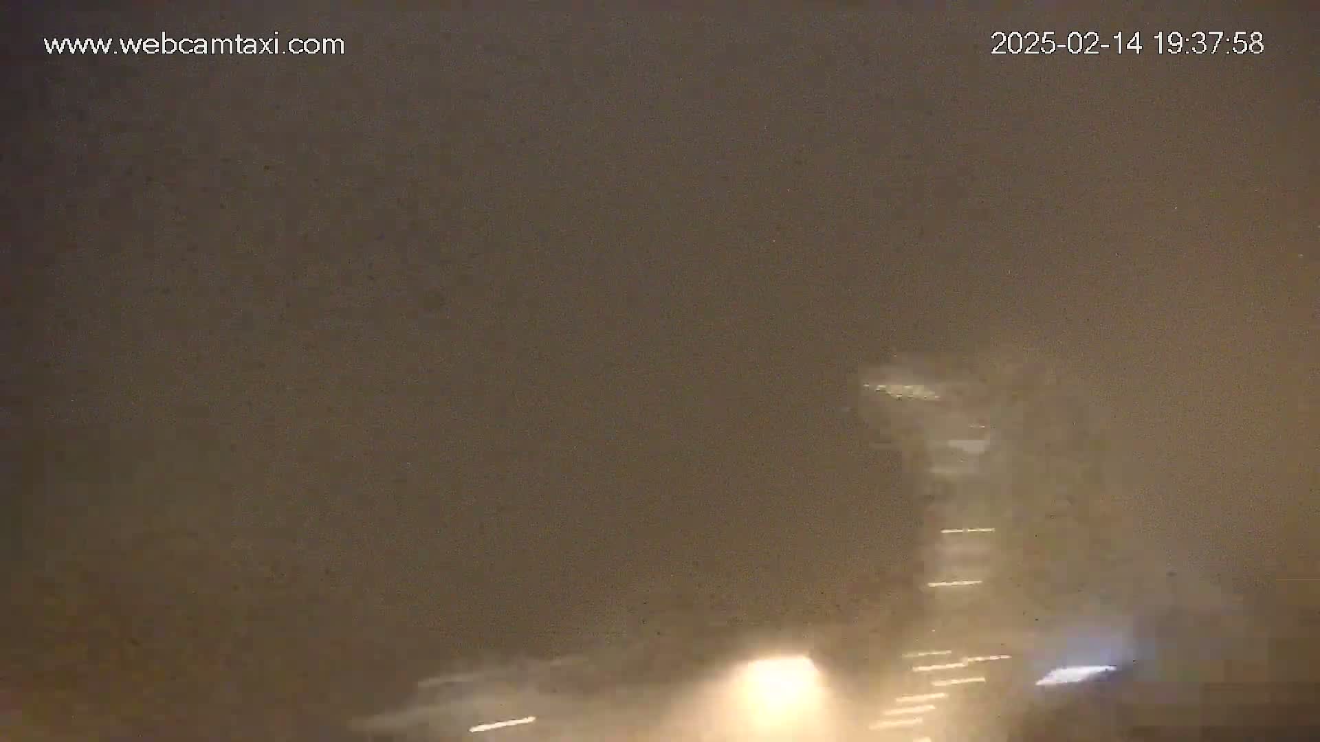 A tall building is partially visible through a hazy, possibly snowy or foggy, night sky.