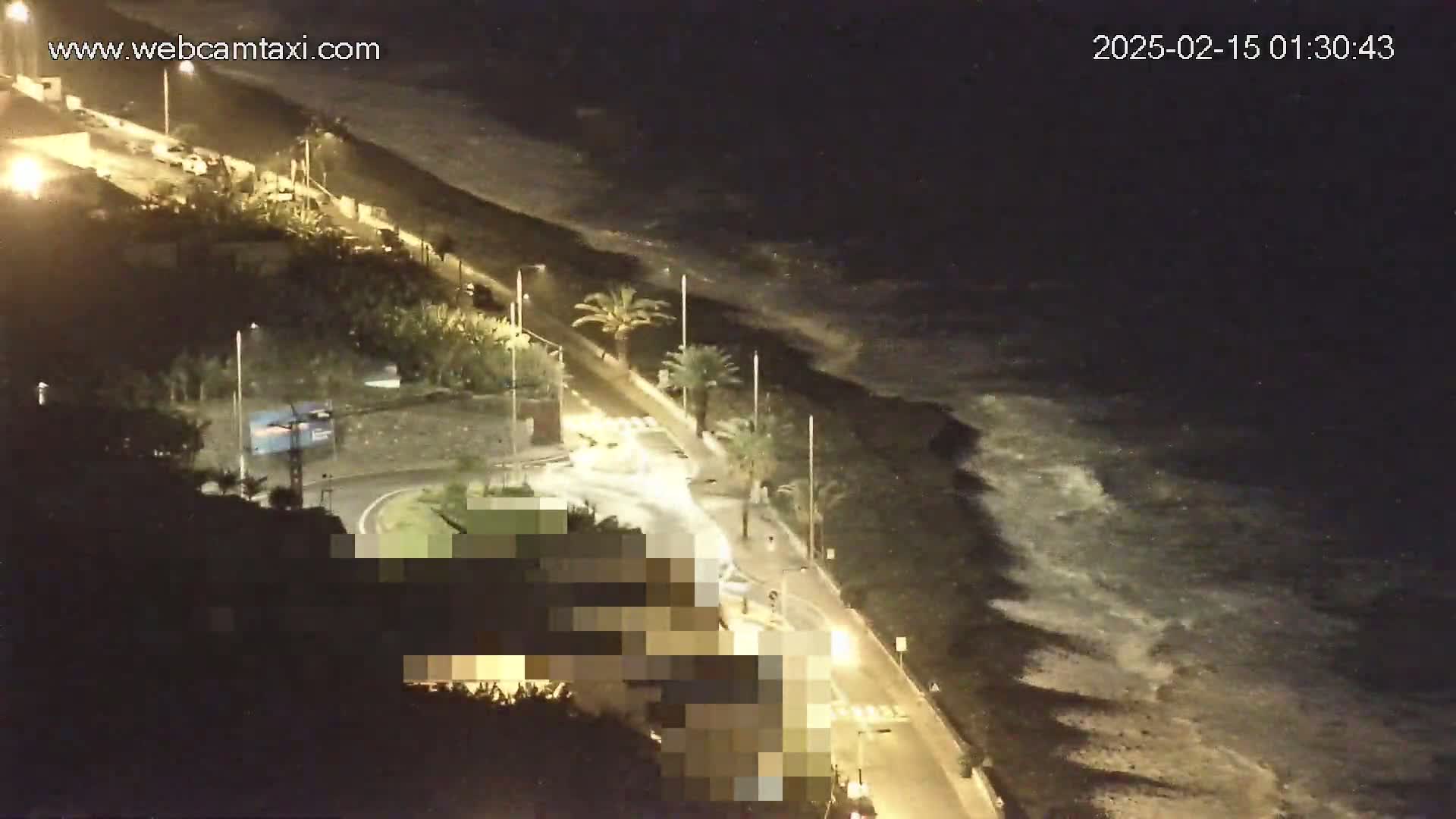 A nighttime coastal road with palm trees is shown, alongside a dark ocean with waves crashing on the shore.
