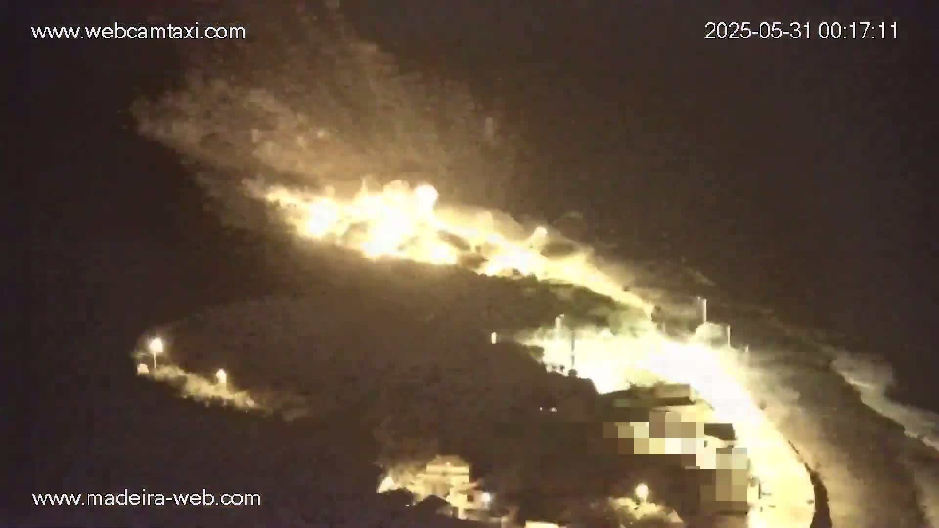A large fire illuminates a hillside at night.