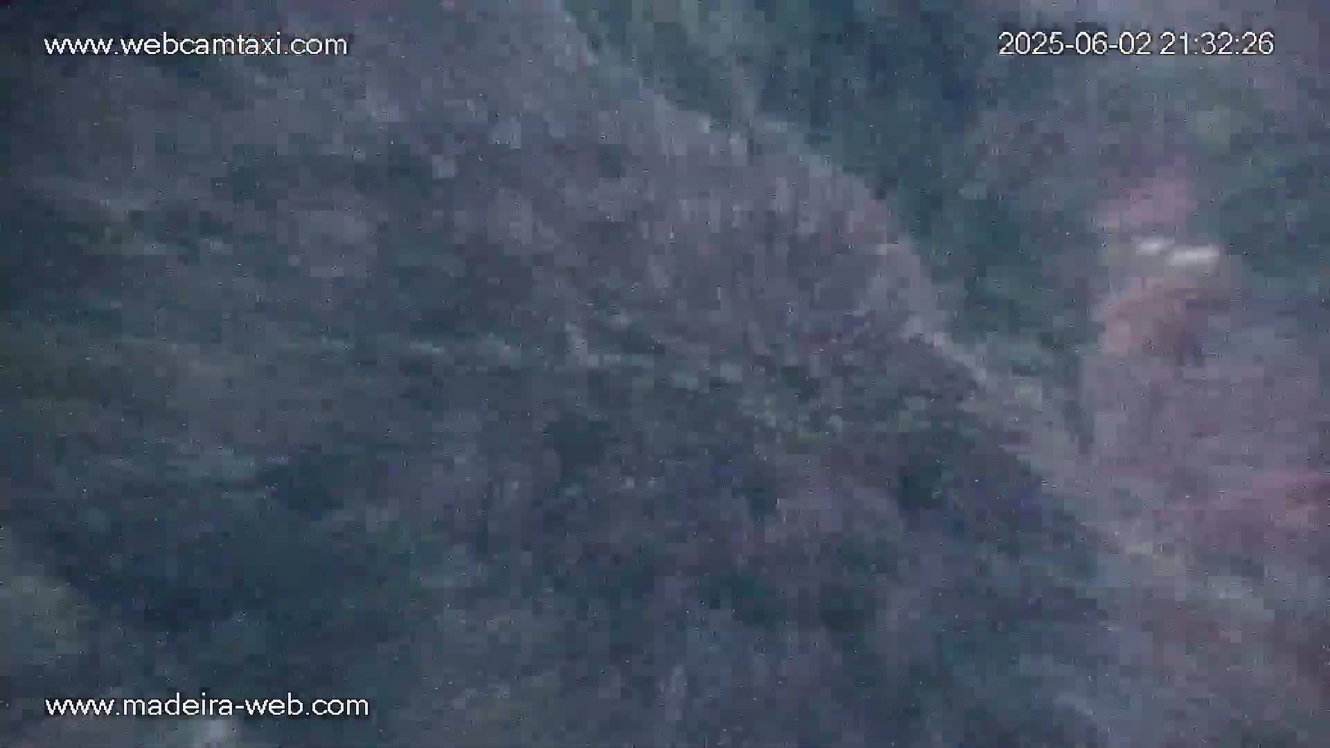 A blurry, dark gray and blue image shows an indistinct, possibly rocky, surface at night.