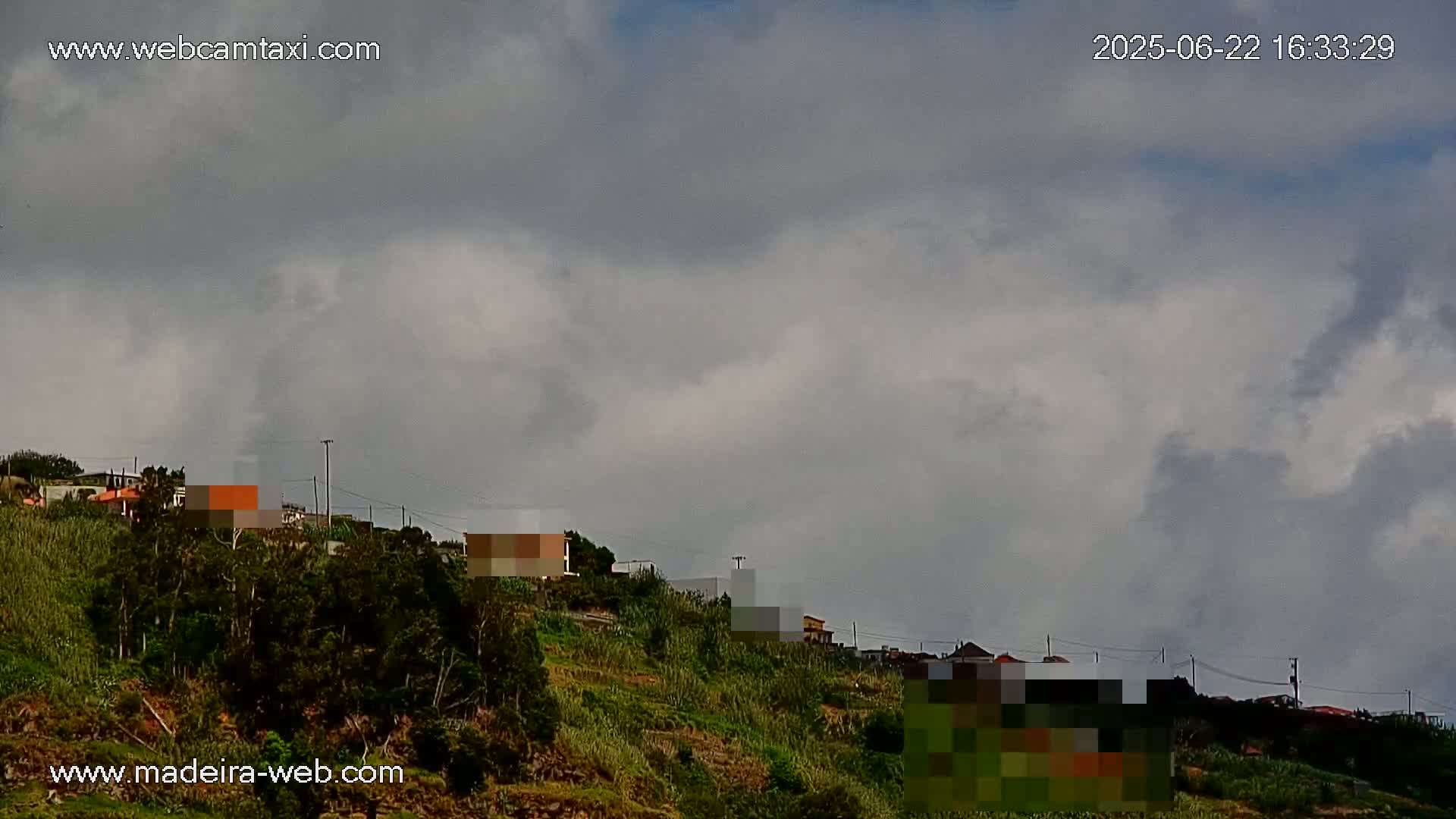 A hillside with houses and vegetation is visible under a mostly cloudy sky.