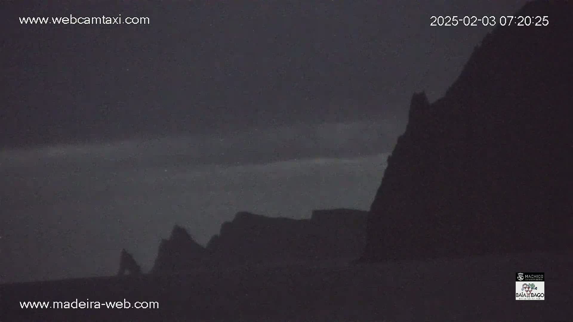 Silhouetted cliffs are visible against a dark, pre-dawn sky.