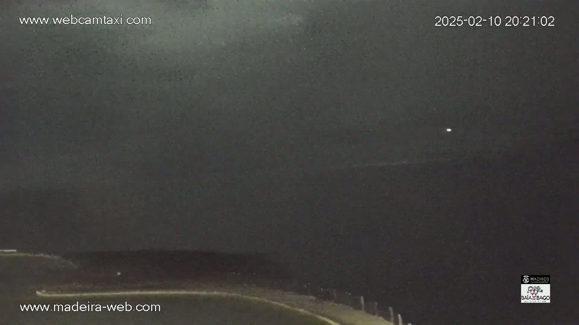 A nighttime, dark, overcast view of a body of water and a shoreline.