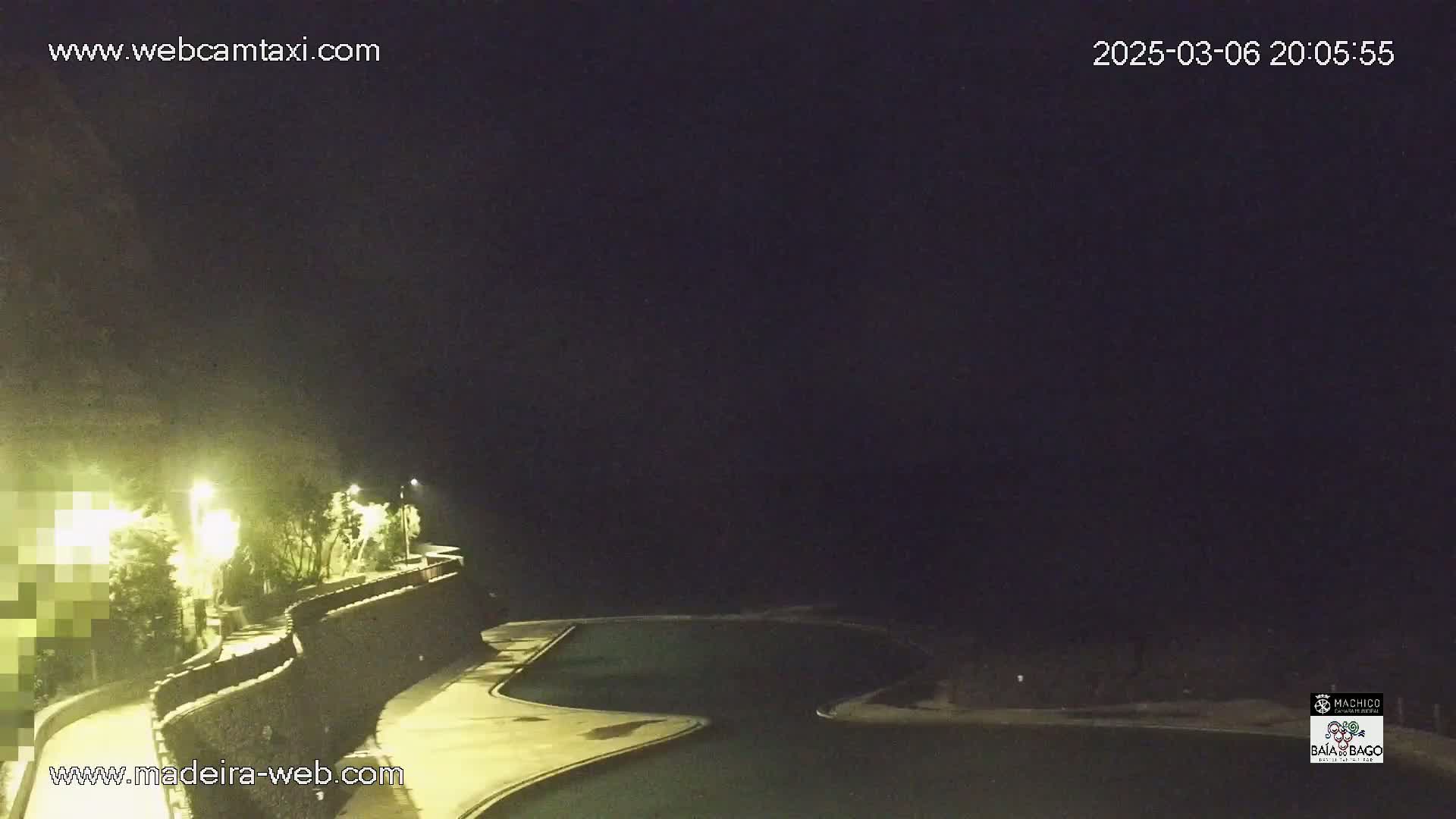 A nighttime view of an empty, illuminated outdoor swimming pool and surrounding landscaping.