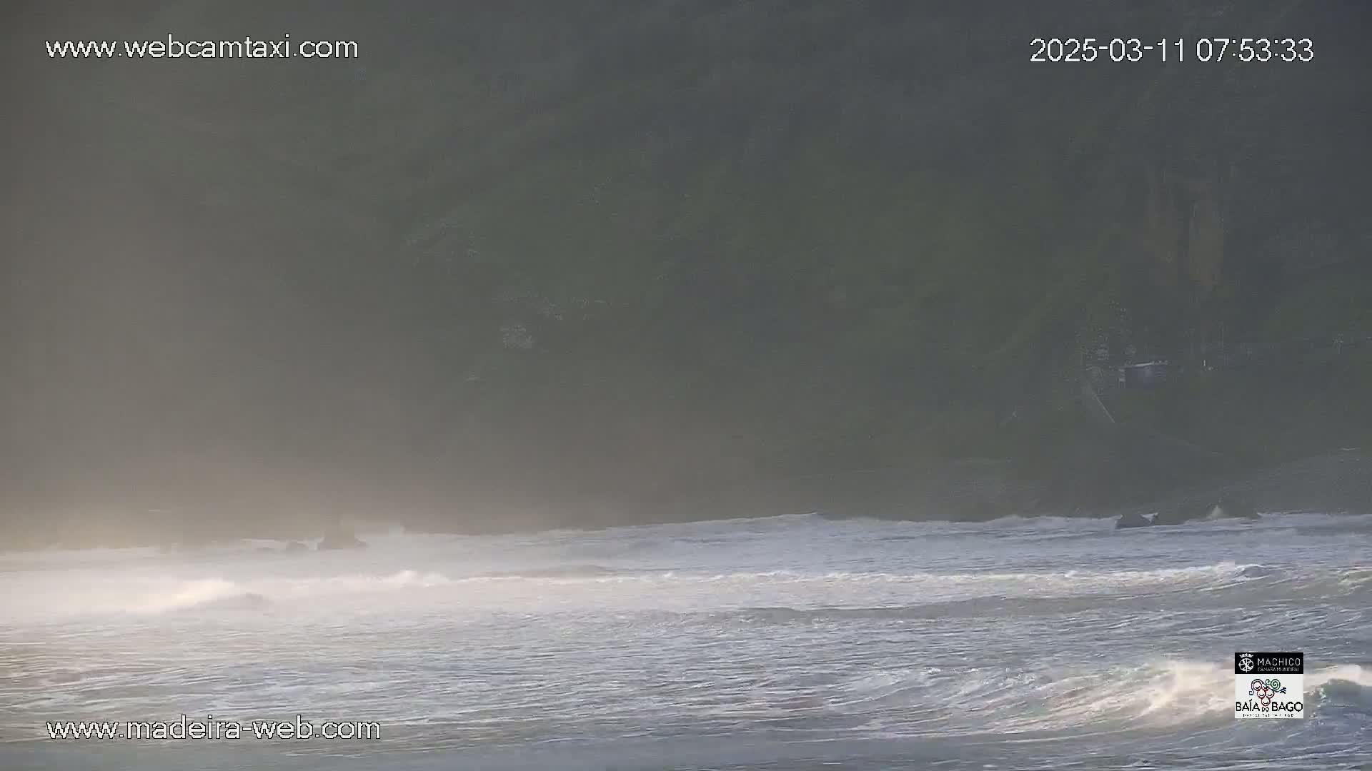 A hazy, misty morning scene shows gentle waves lapping at a dark shoreline.