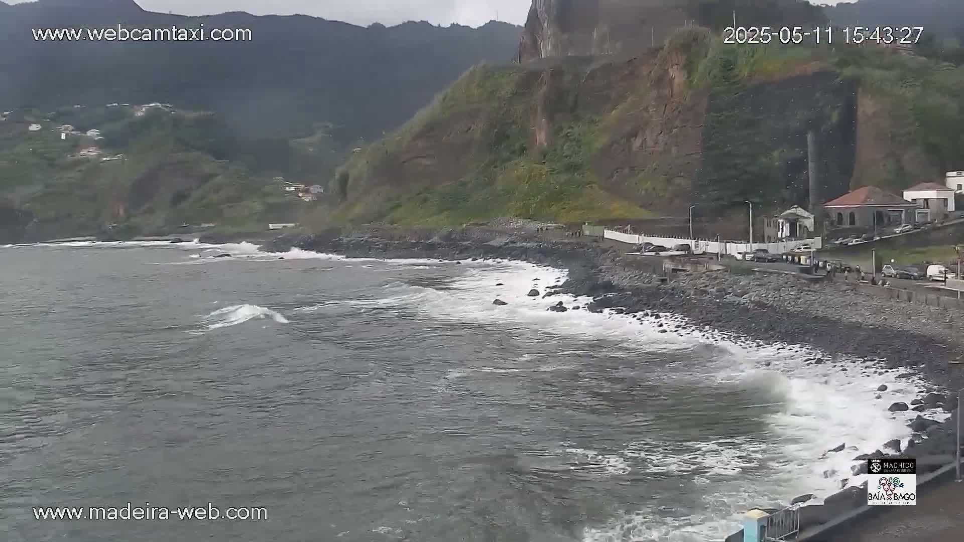 A rocky coastline with small waves under an overcast sky.