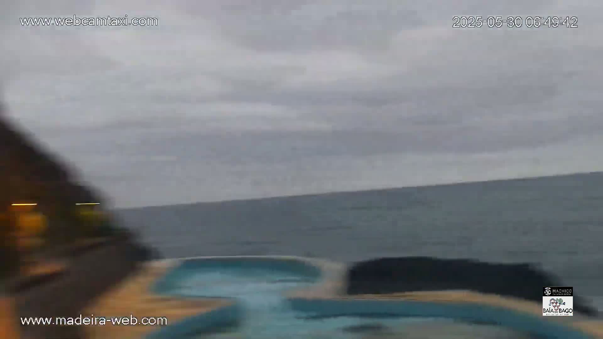 A blurry view of a swimming pool and the ocean under an overcast sky.