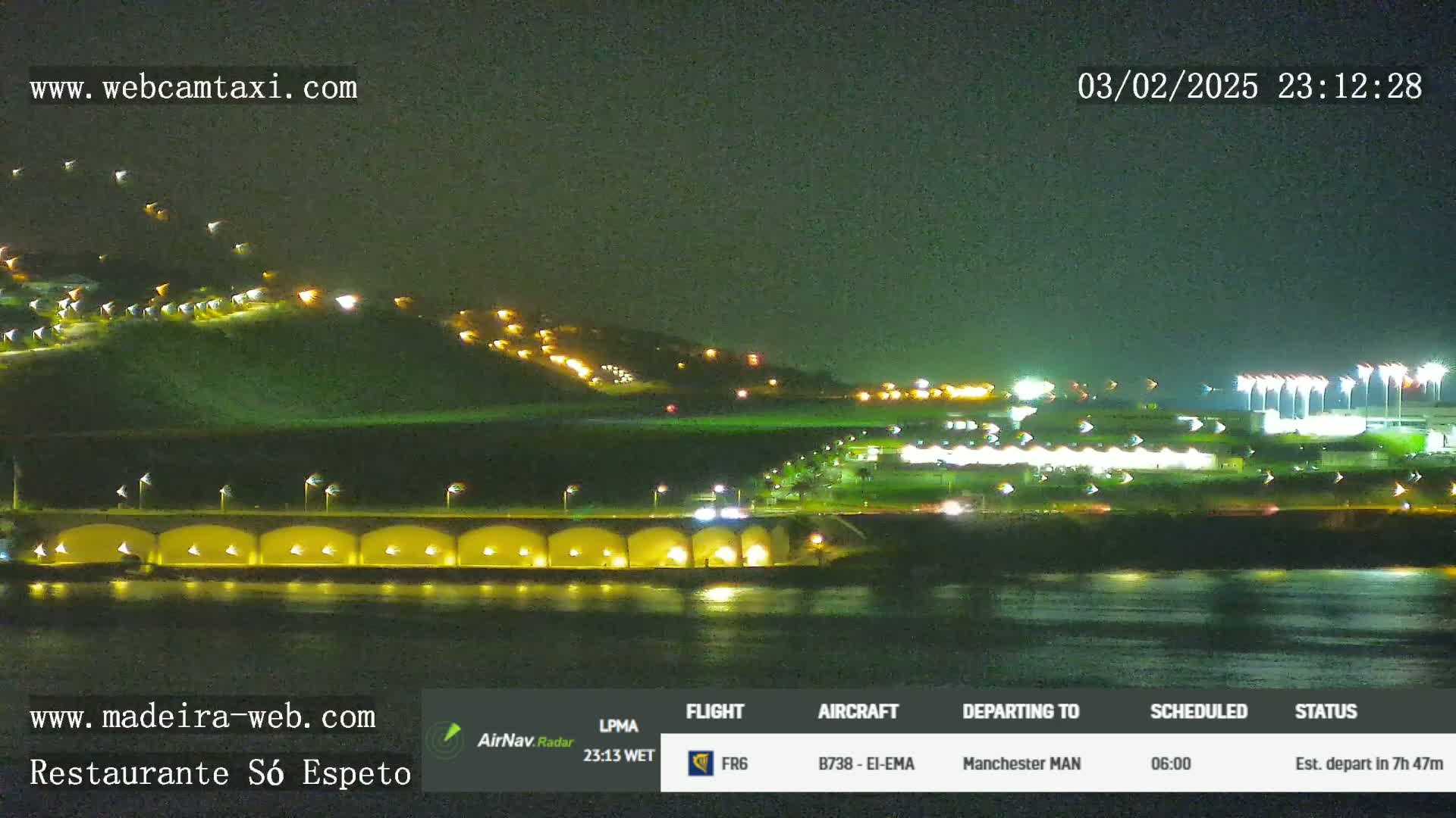 A nighttime view of a brightly lit coastline with a body of dark water in the foreground.
