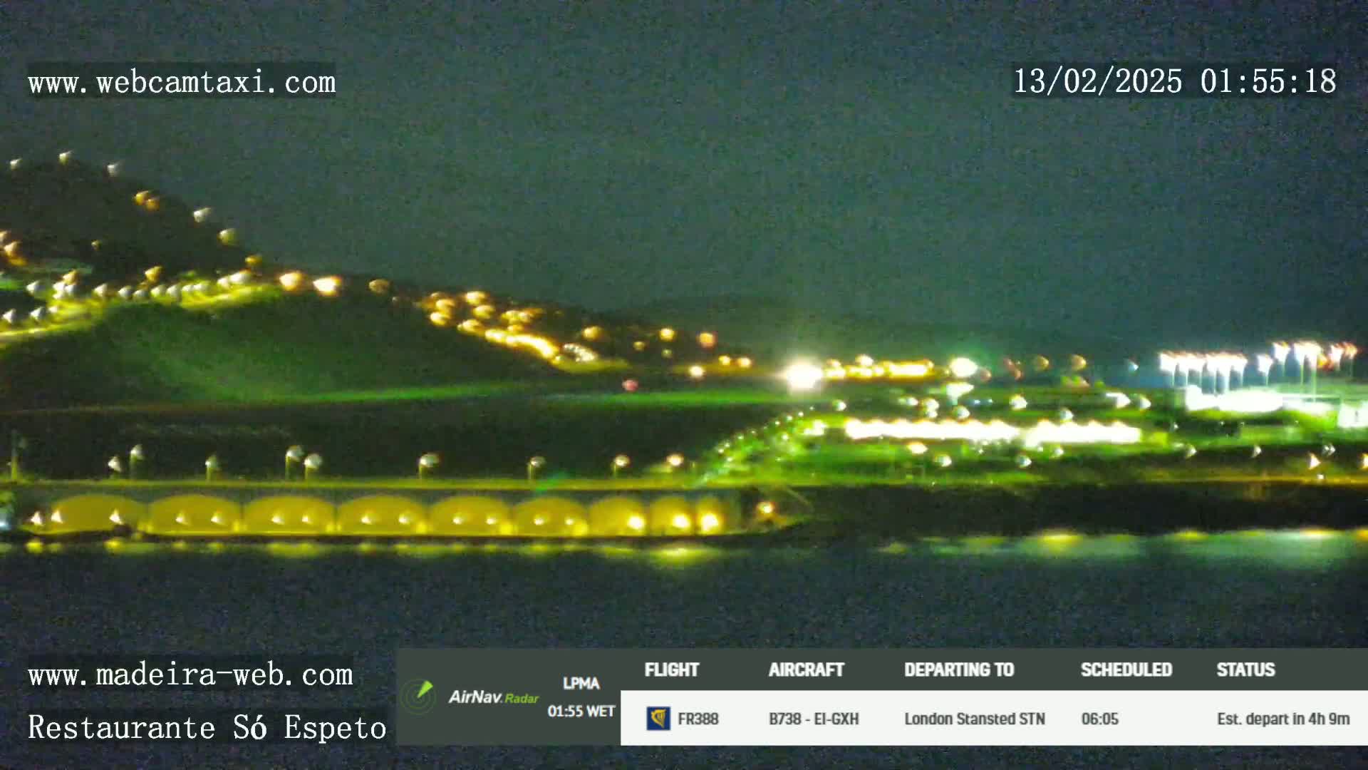 A nighttime long shot shows a hilltop with scattered lights, a lighted bridge, and a dark body of water.