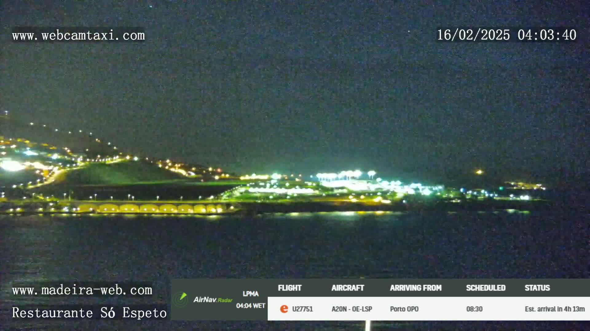 A nighttime, coastal view of a brightly lit airport and city under a clear, dark sky.