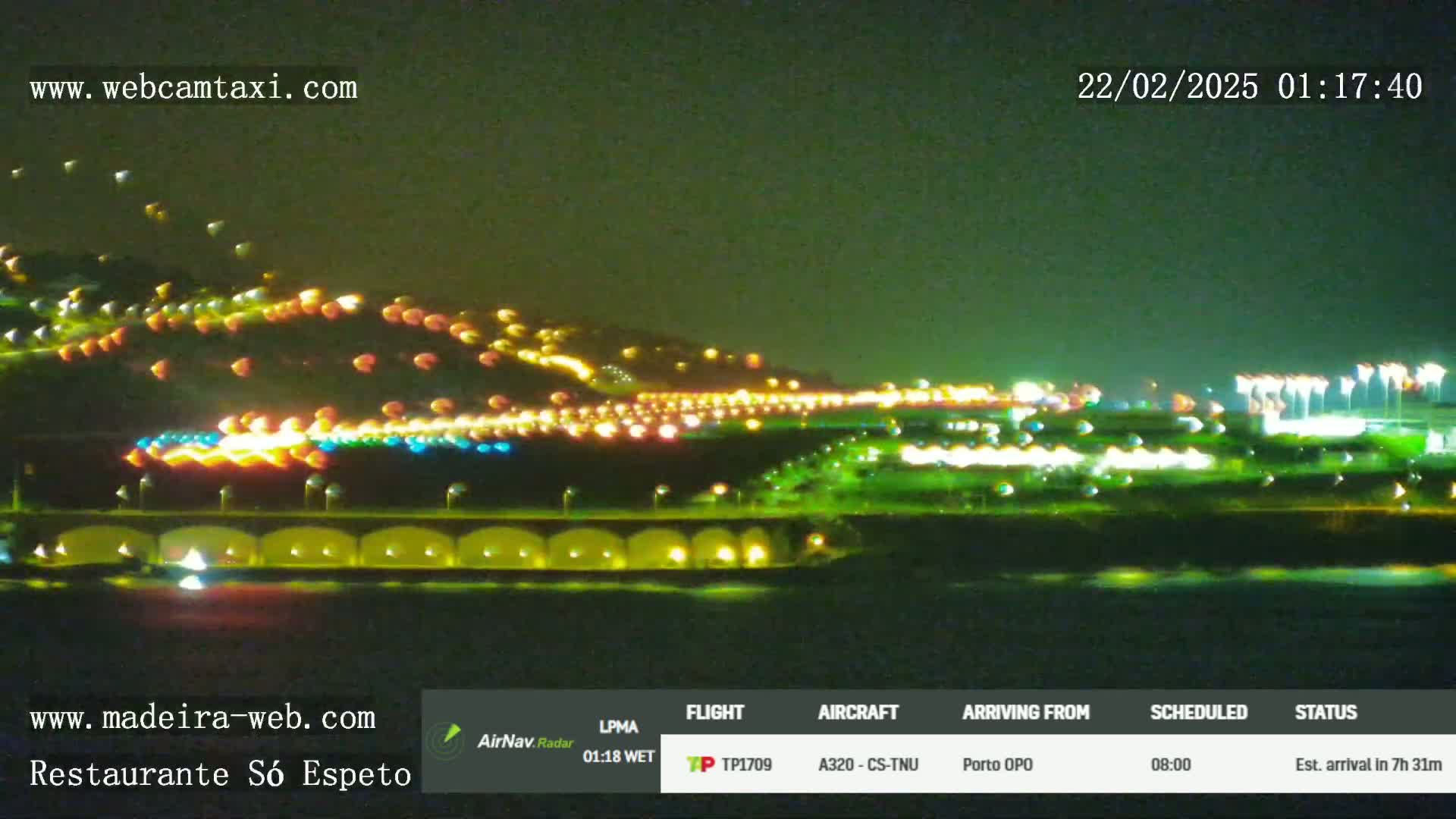 A nighttime view of a city's illuminated coastline, with numerous lights visible on hills and along the water's edge.