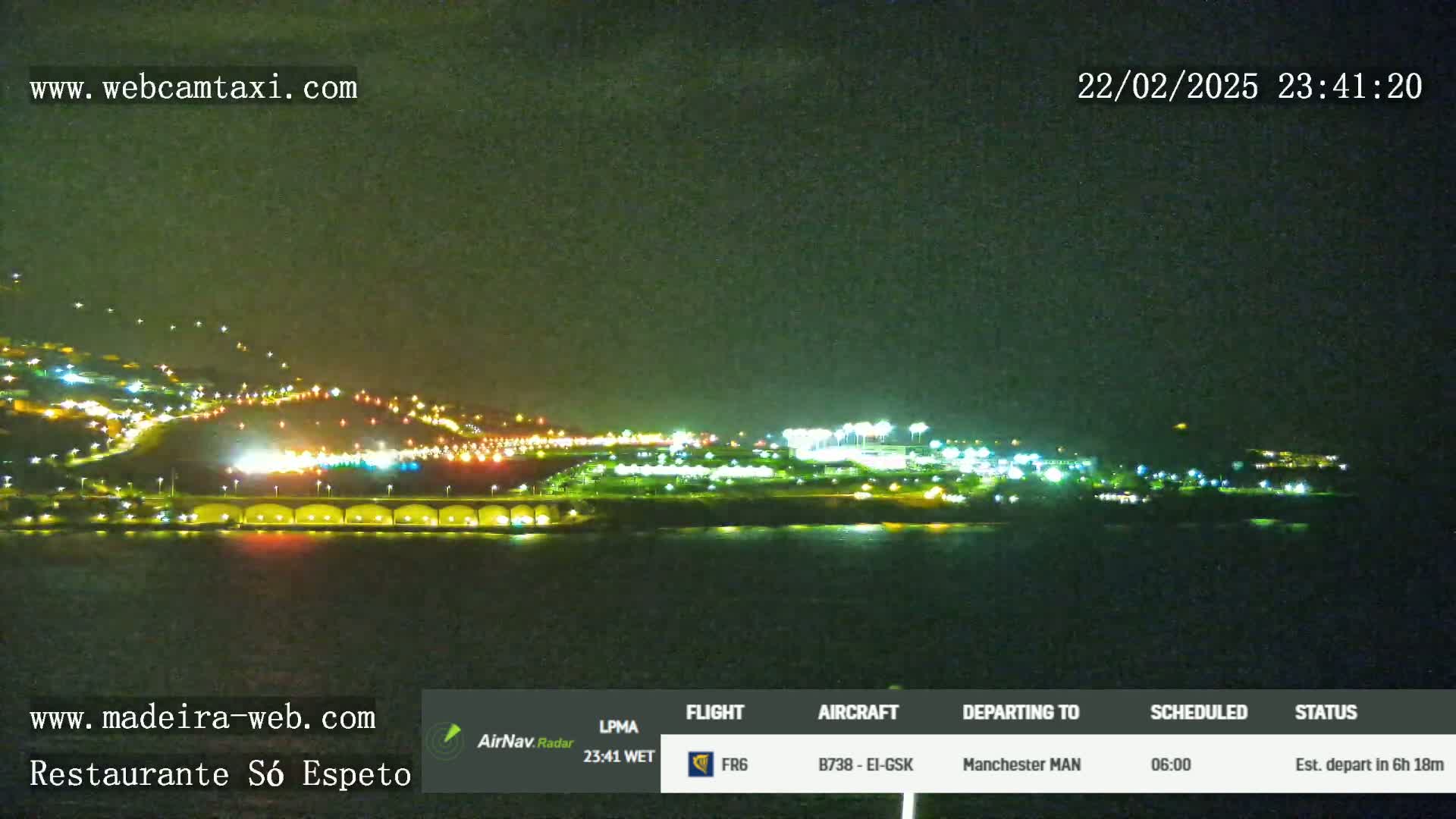 A nighttime view of a brightly lit coastal city at night, next to dark water.