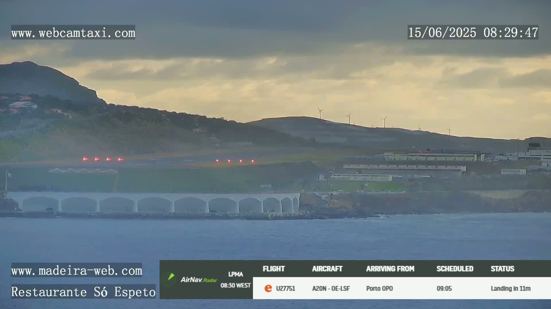 An airplane is landing at an airport by the ocean under partly cloudy skies.