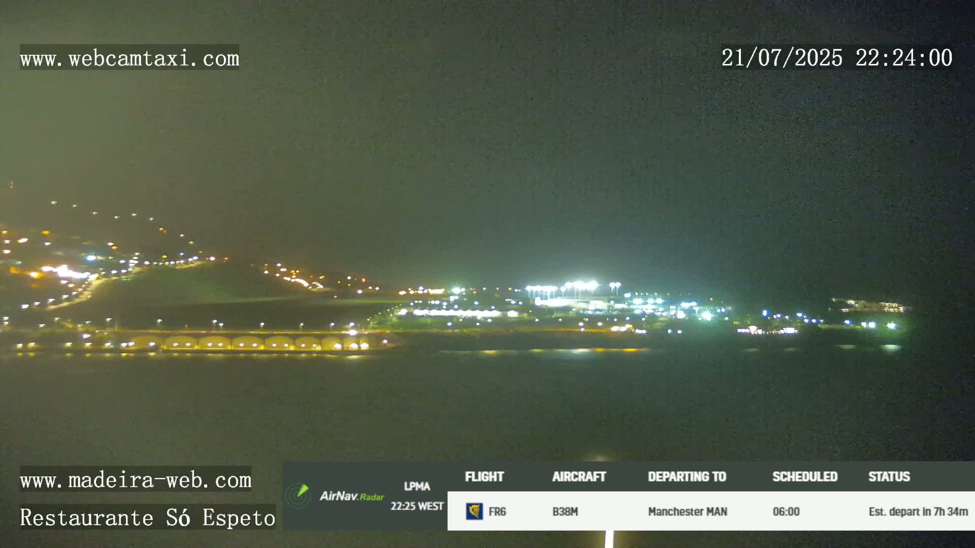 A nighttime long shot of an airport with lights illuminating runways and buildings, under a dark, clear sky.