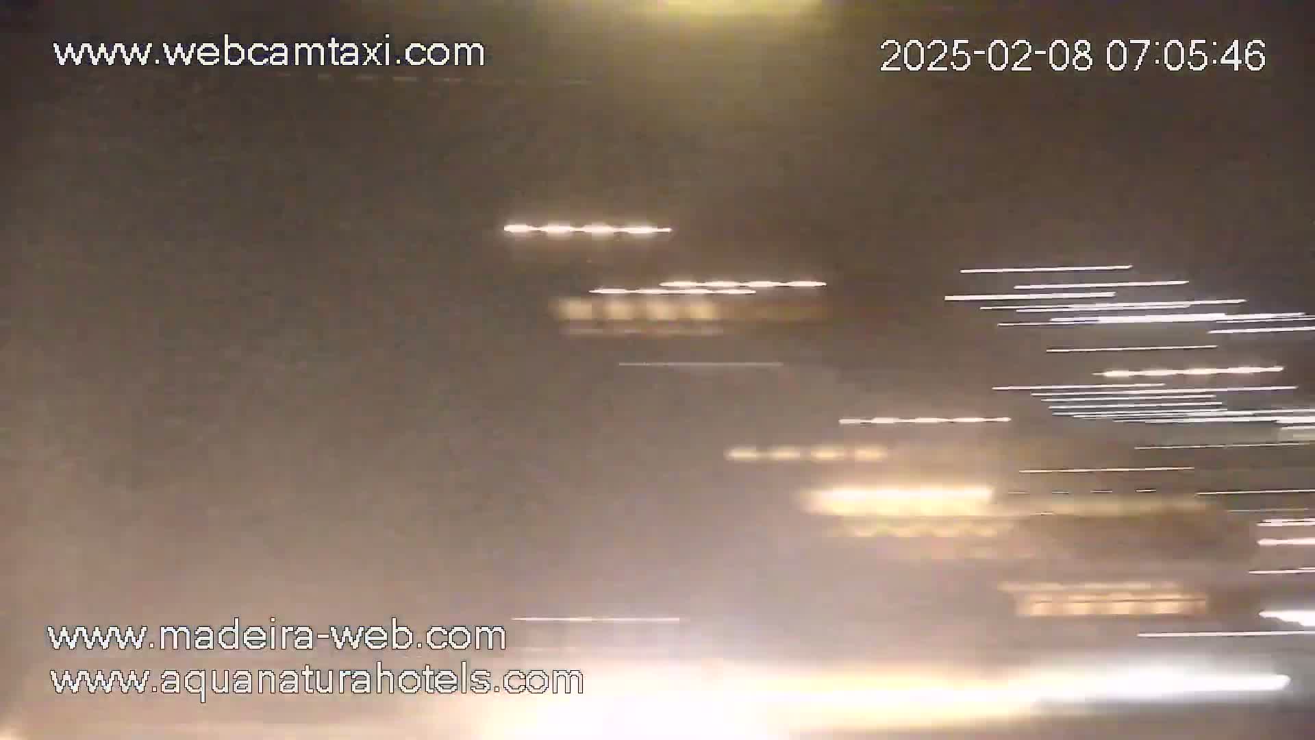 Streaks of light from vehicles moving at night are visible through a hazy or foggy atmosphere.