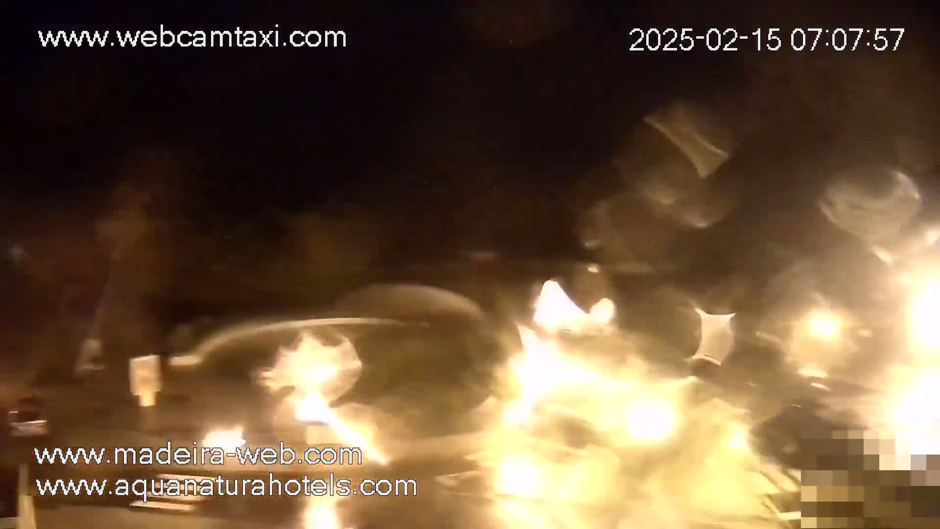 A nighttime, low-light video shows a blurry scene of what appears to be a vehicle accident with bright lights and flames.