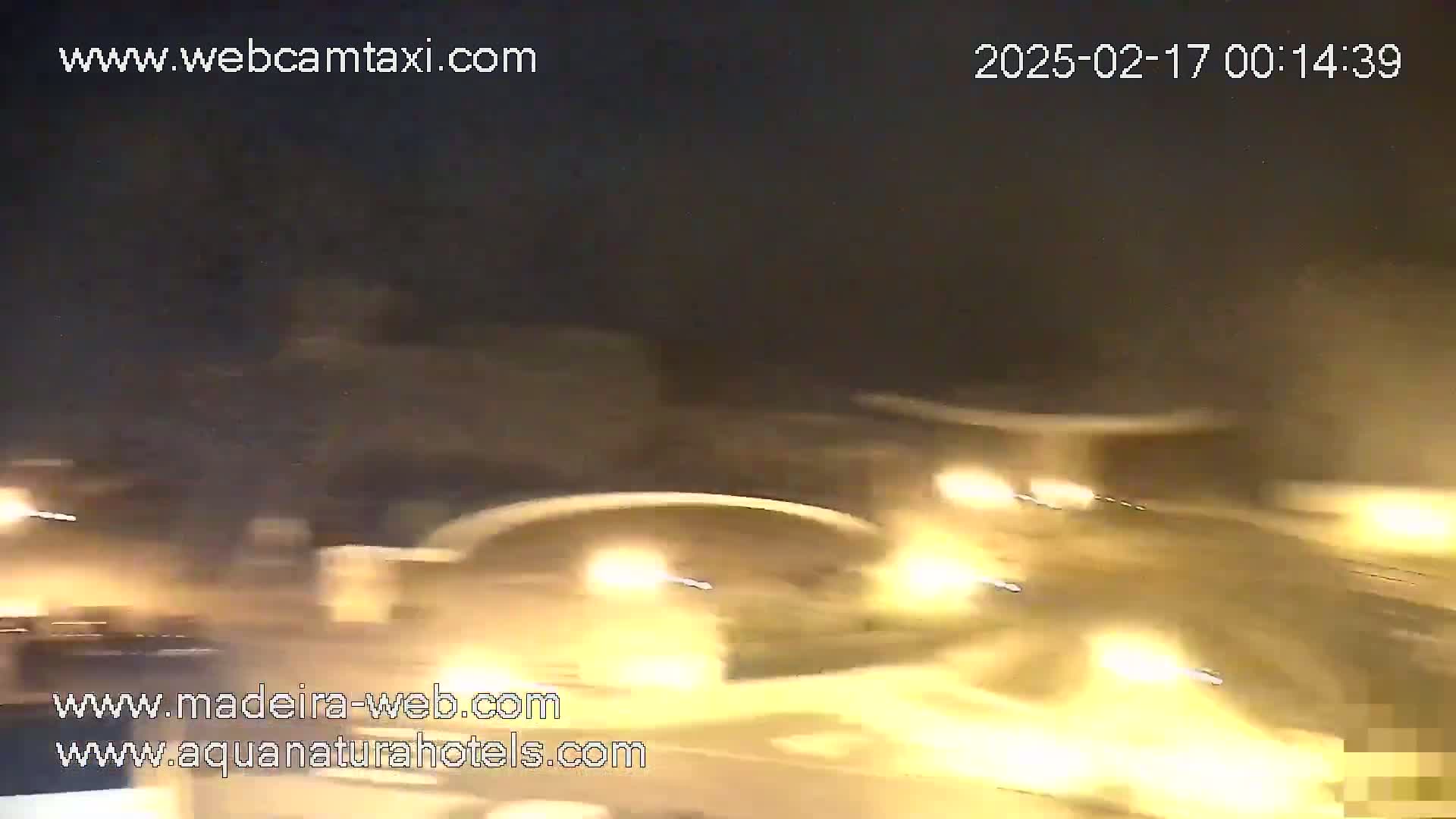 A nighttime, blurry view of a roadway with bright headlights from moving vehicles.