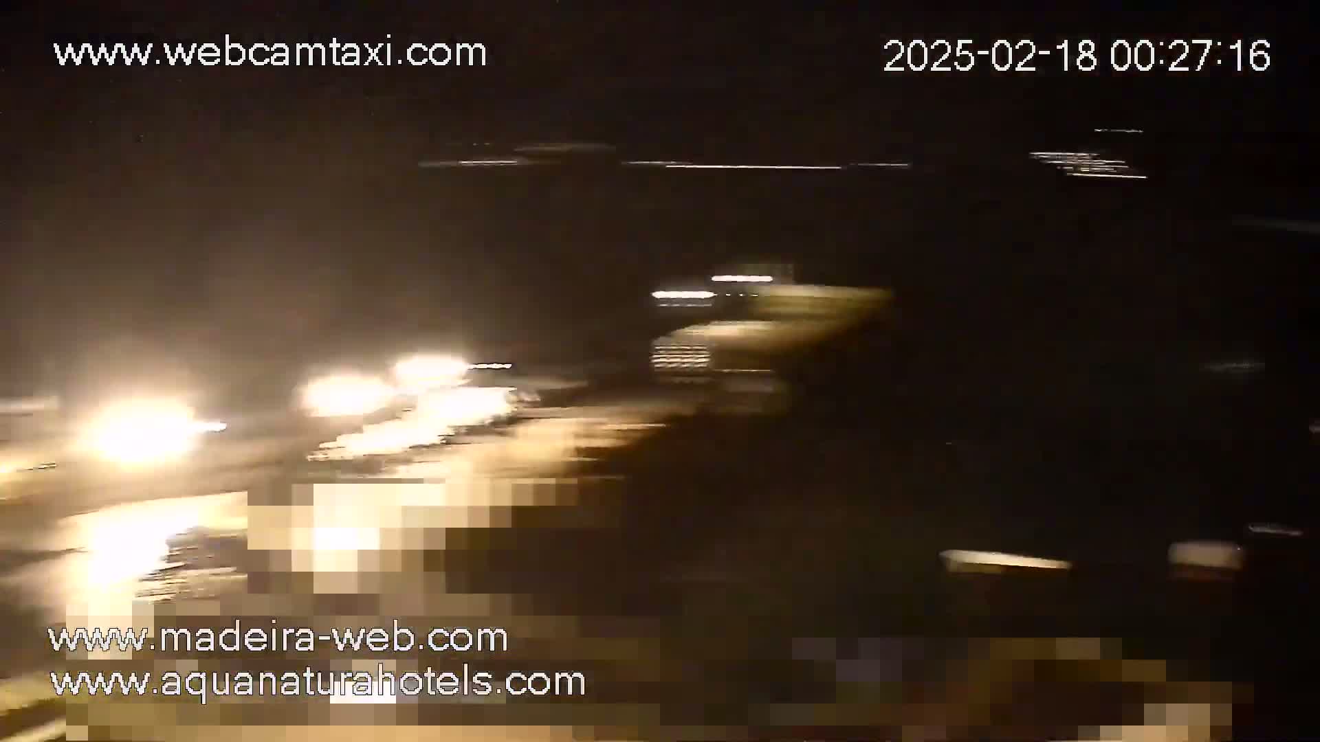 A nighttime view of a road with blurred headlights of vehicles traveling in both directions.